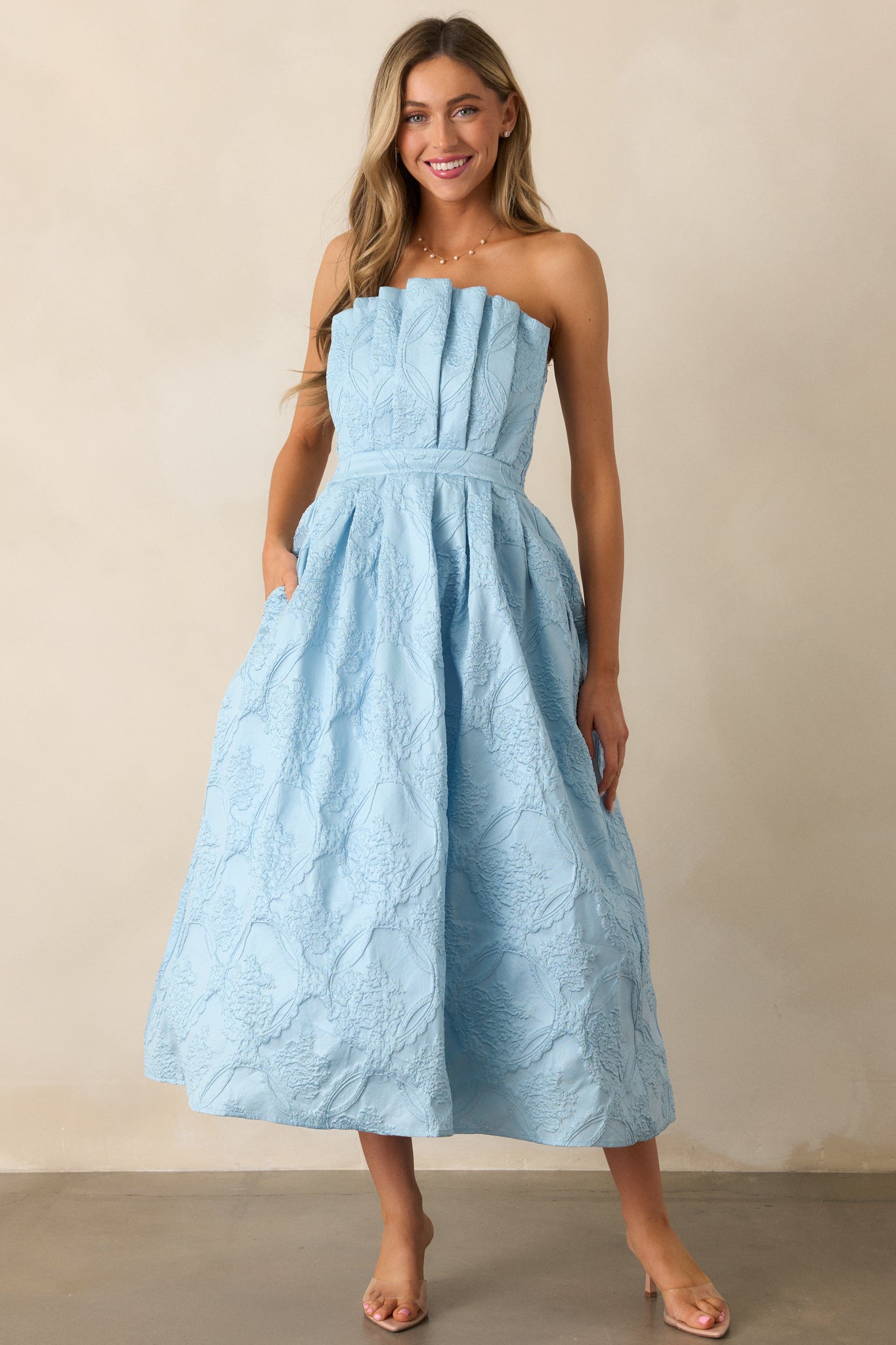  The sky blue midi dress highlighting the smooth pleats, jacquard design, and flattering strapless cut.
