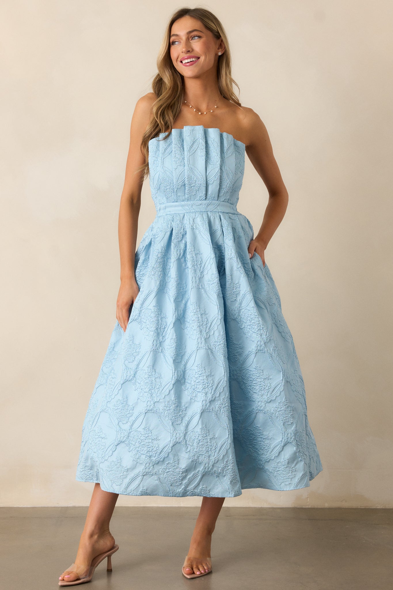 A sky blue midi dress with a pleated bodice, slightly pleated skirt, jacquard design, and strapless silhouette.