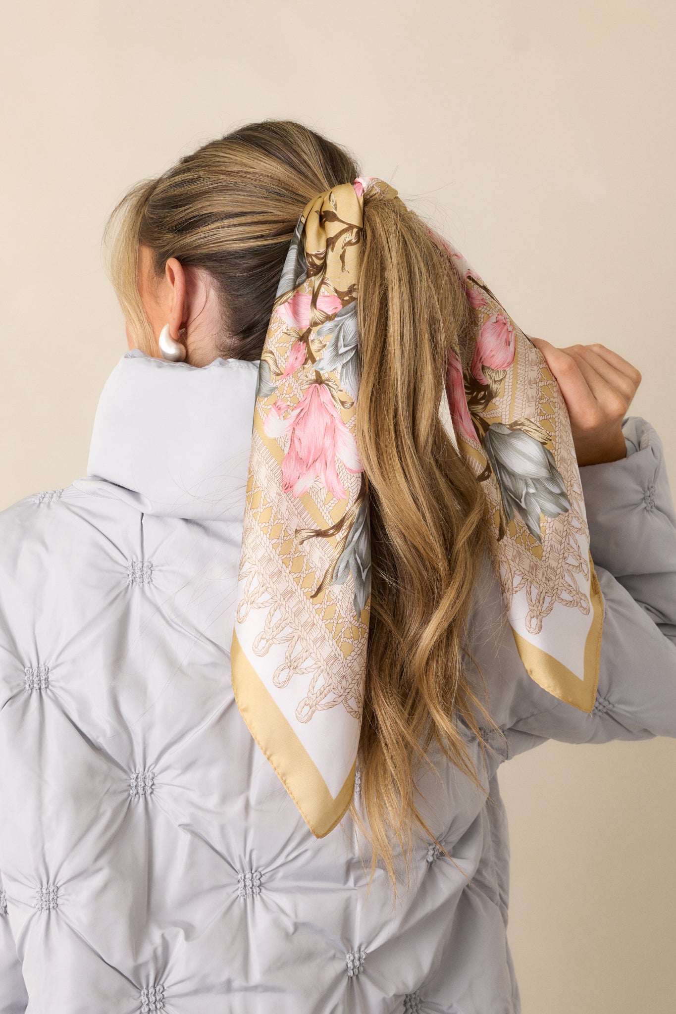 A full-length view of the gold scarf, featuring a satin material with a pink and blue floral design, and accented with gold trim.