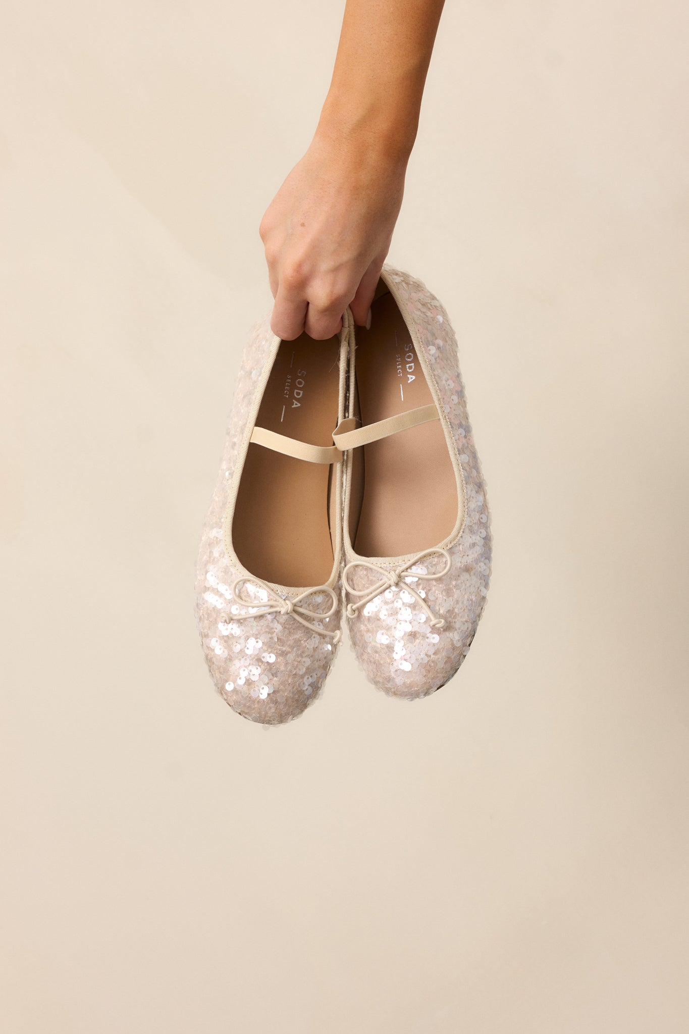 A focus on the beige sequin flats showing the across-the-foot strap and subtle sequin texture.