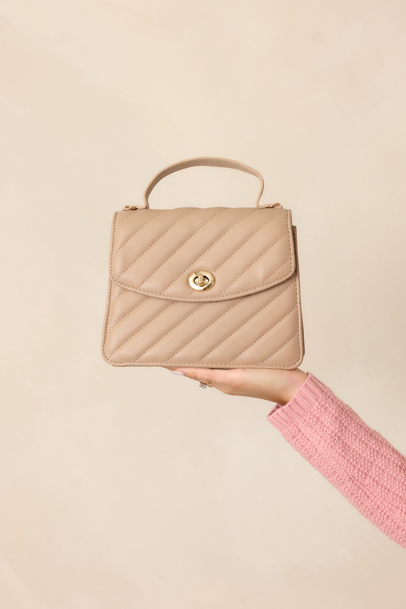 A complete look of the handbag's gold twist lock closure, focusing on the intricate detail of the quilted material and the thin solid handle.