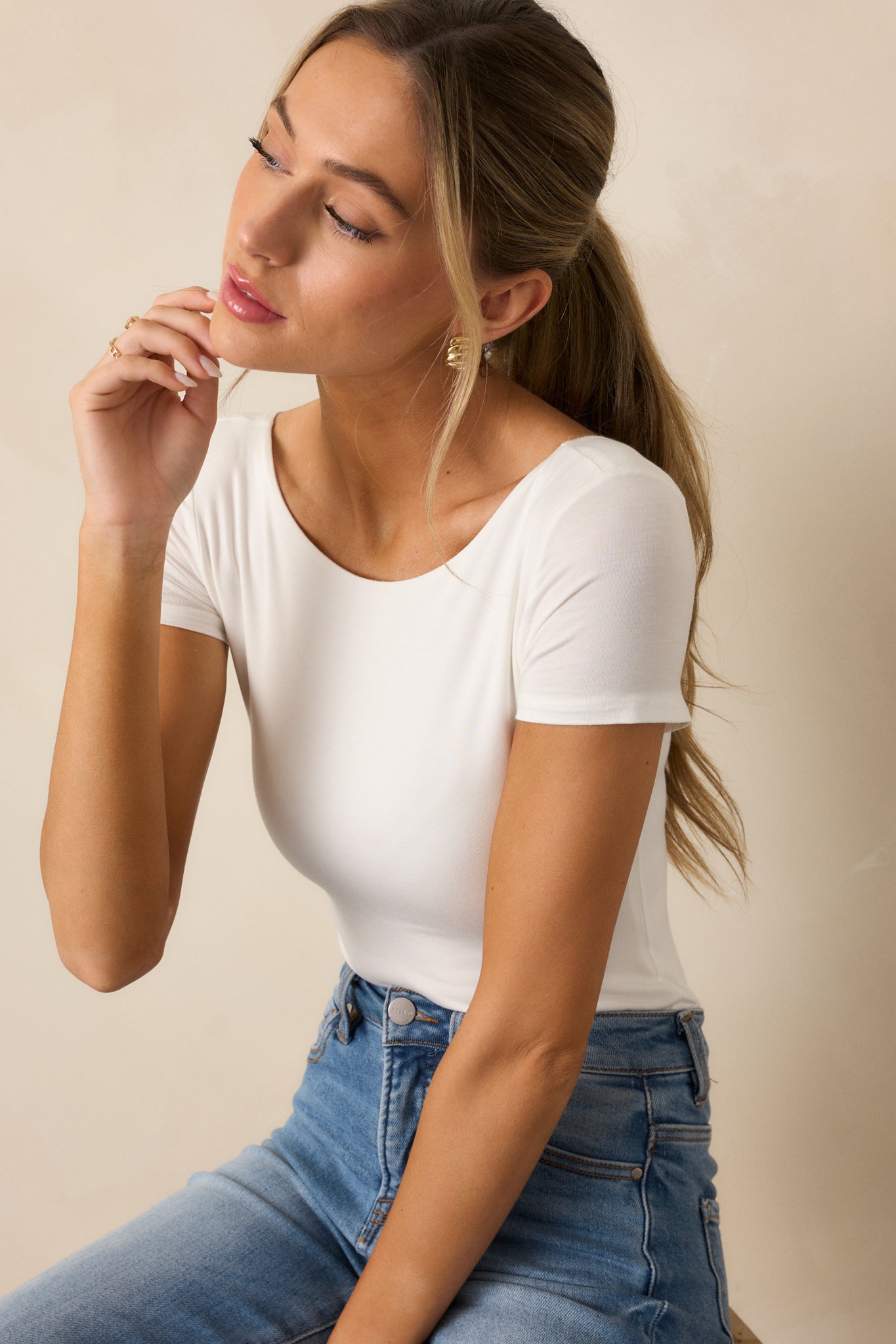 The white bodysuit from another angle, emphasizing its sleek, fitted silhouette, scoop neckline, and short sleeves.