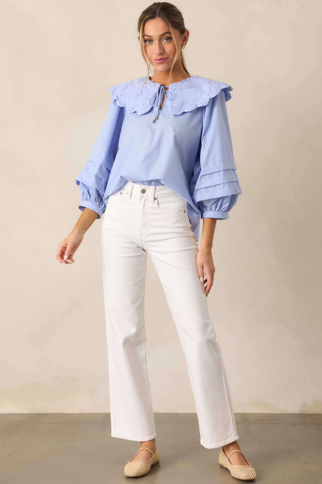 A full-length view of the white jeans showcasing their high-waisted design, straight leg cut, and functional pockets and belt loops, with the button and zipper closure visible at the waist.