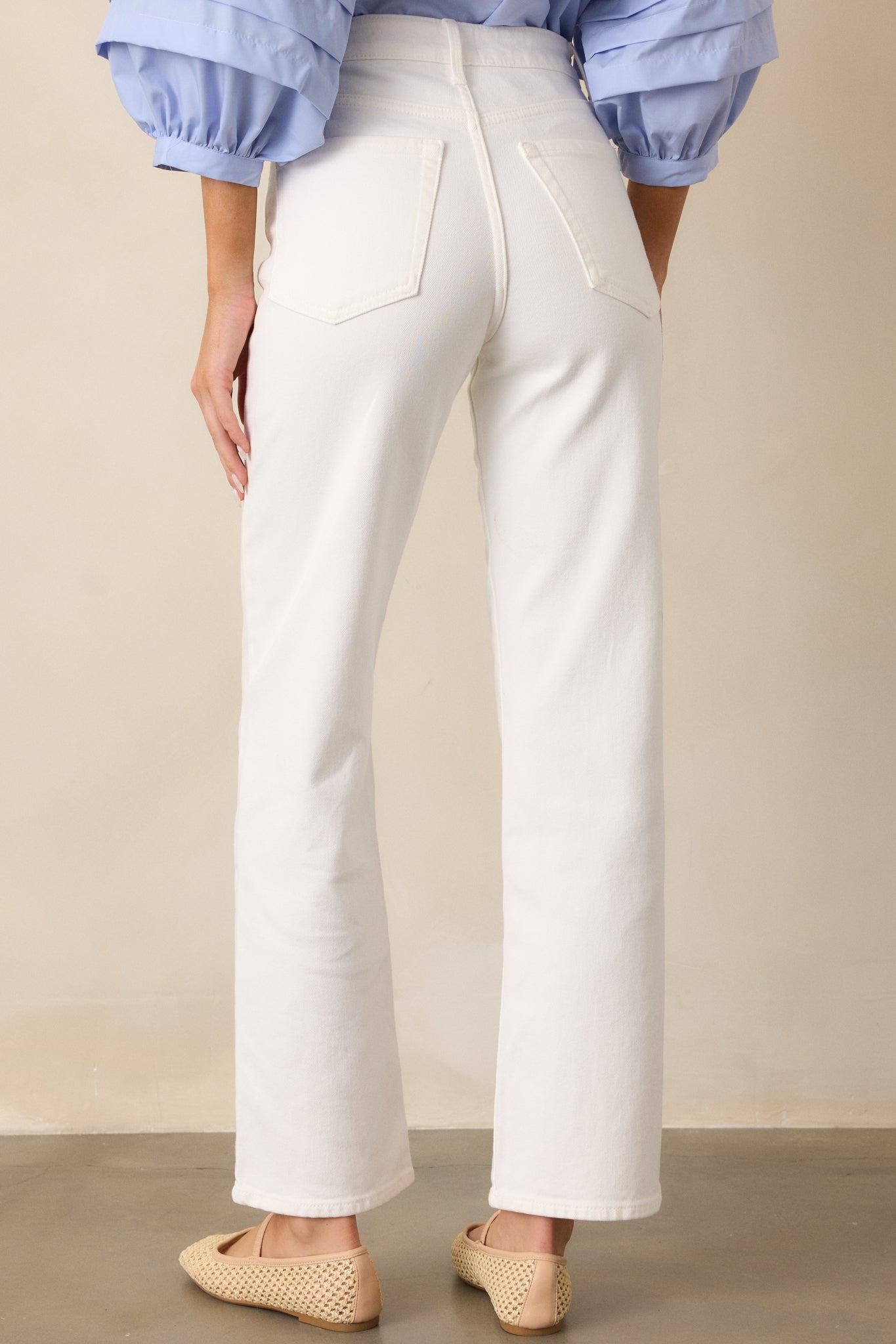 A back view of the white jeans, emphasizing the straight leg cut, with the functional back pockets visible, and the high-waisted fit continuing around the waistband.