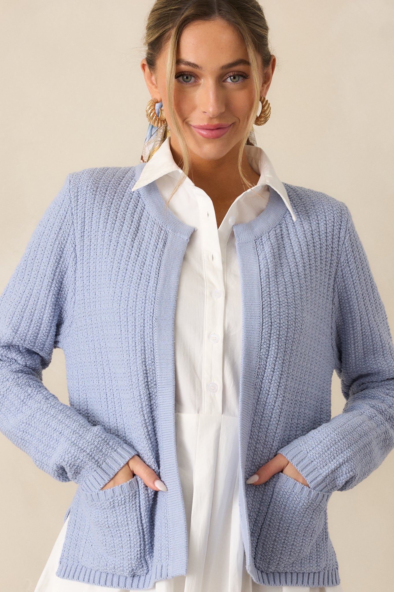 Cropped view of the blue cardigan focusing on the rounded neckline and upper knit design.