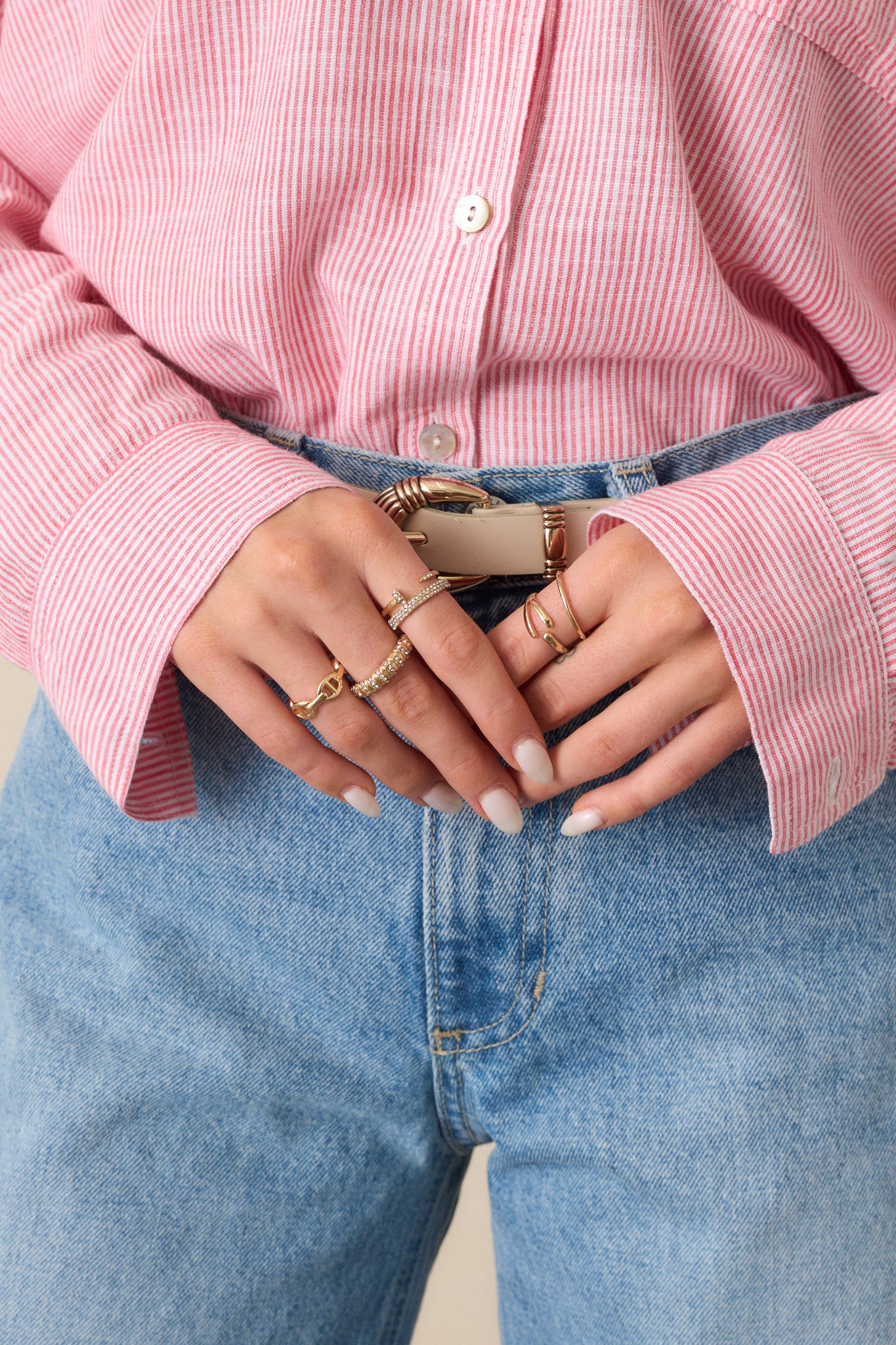 A focused view of the gold ring stack, showcasing the six rings, including a simple thin gold band, an adjustable ring with circular designs, a wishbone adjustable ring, a thick gold pave rhinestone ring, and two rhinestone pave adjustable rings stacked together.