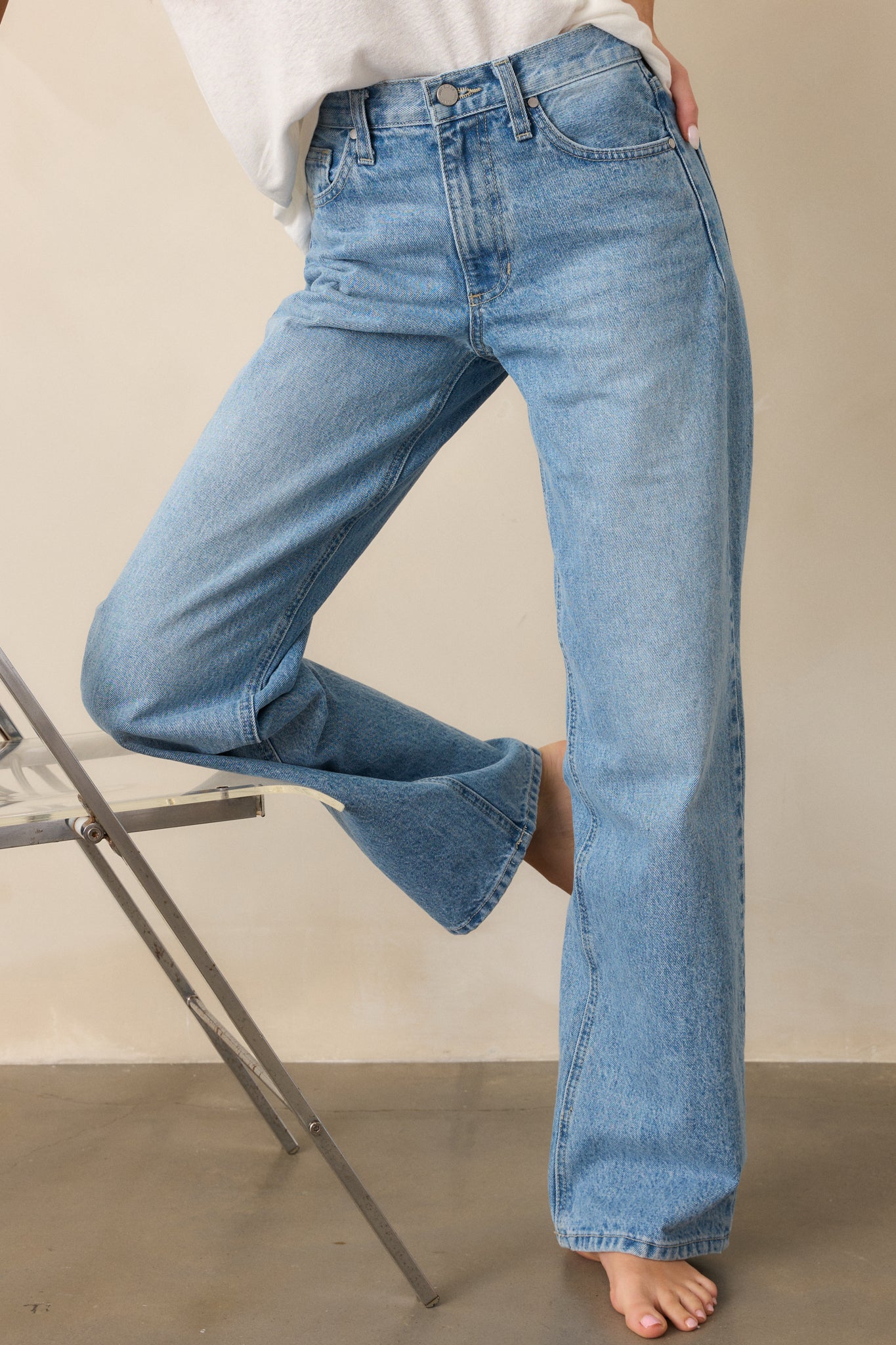 A cropped view of the jeans from the front, focusing on the waist area, showing the high-rise design, button and zip closure, and relaxed fit of the pants.