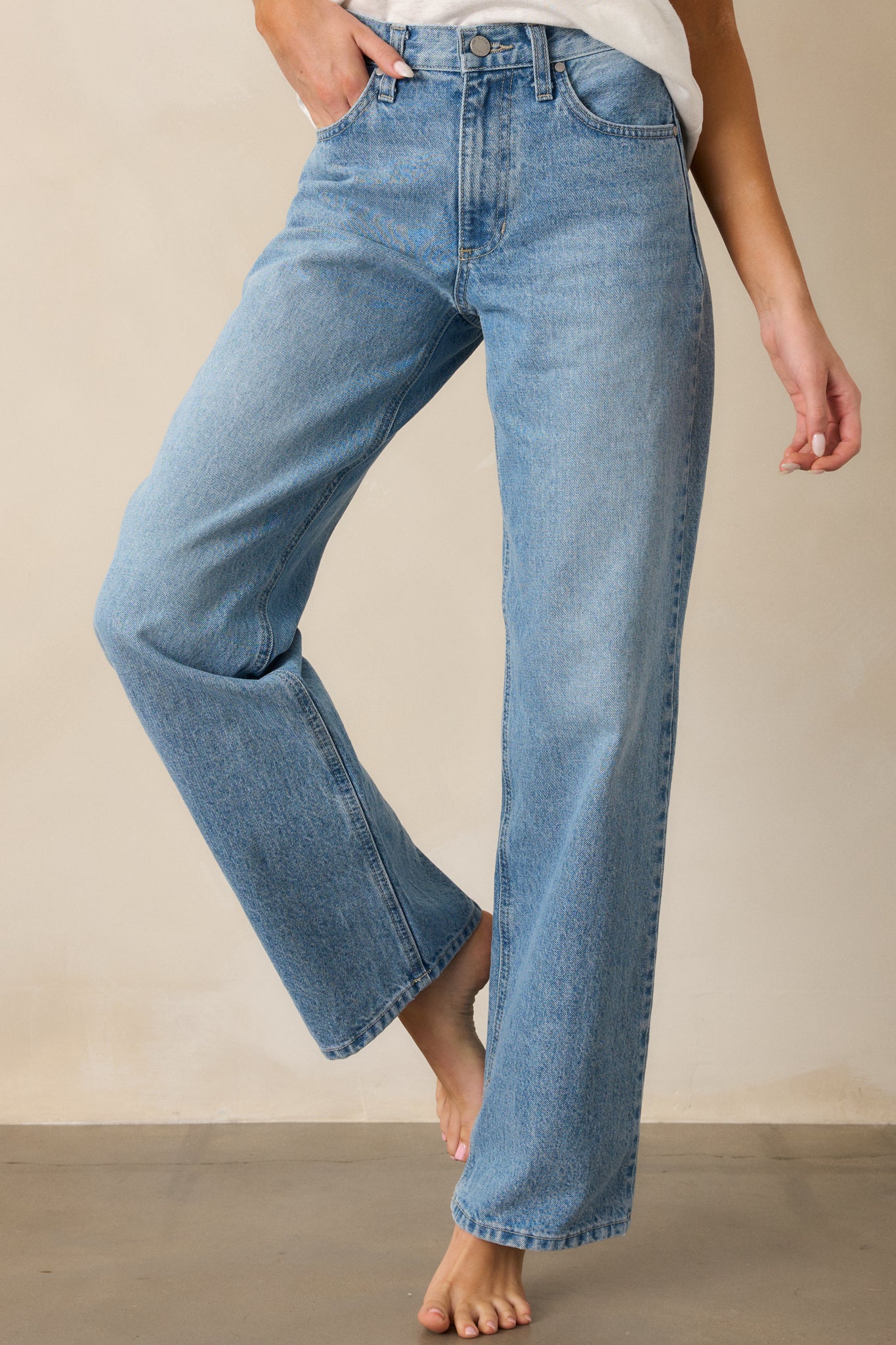 A focused shot on the front of the jeans, emphasizing the relaxed fit, high waist, and straight leg cut with visible stitching along the front.