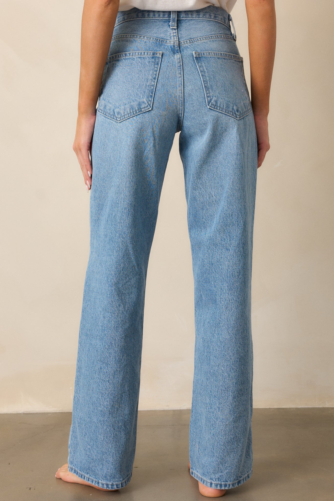 A back view of the light wash jeans, highlighting the relaxed fit and straight leg cut, with a clear view of the waistband and stitching.