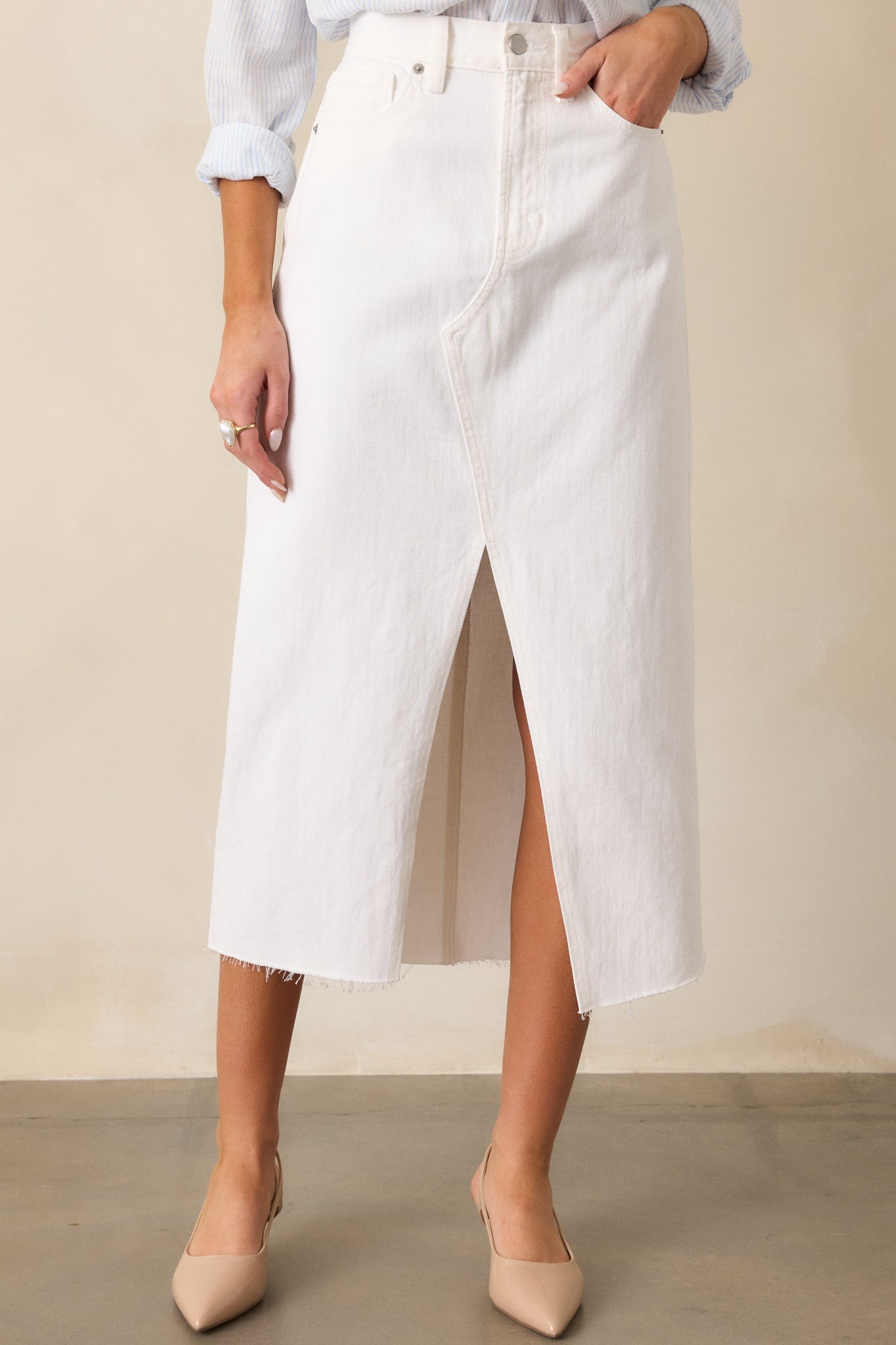 The white skirt is shown focusing on the raw bottom hem and detailed stitching near the slit.