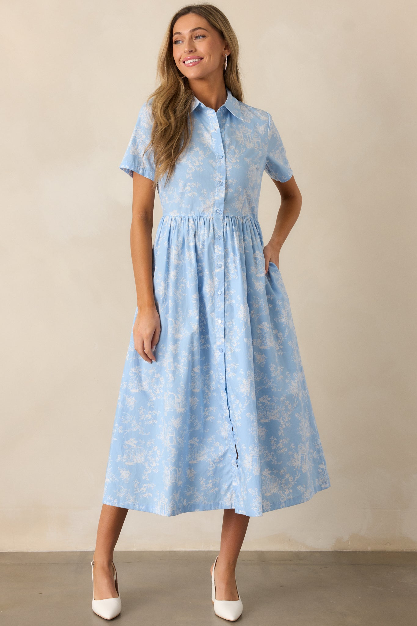 A light blue maxi dress showcasing the gathering at the waist, functional hip pockets, and a vibrant toile pattern.