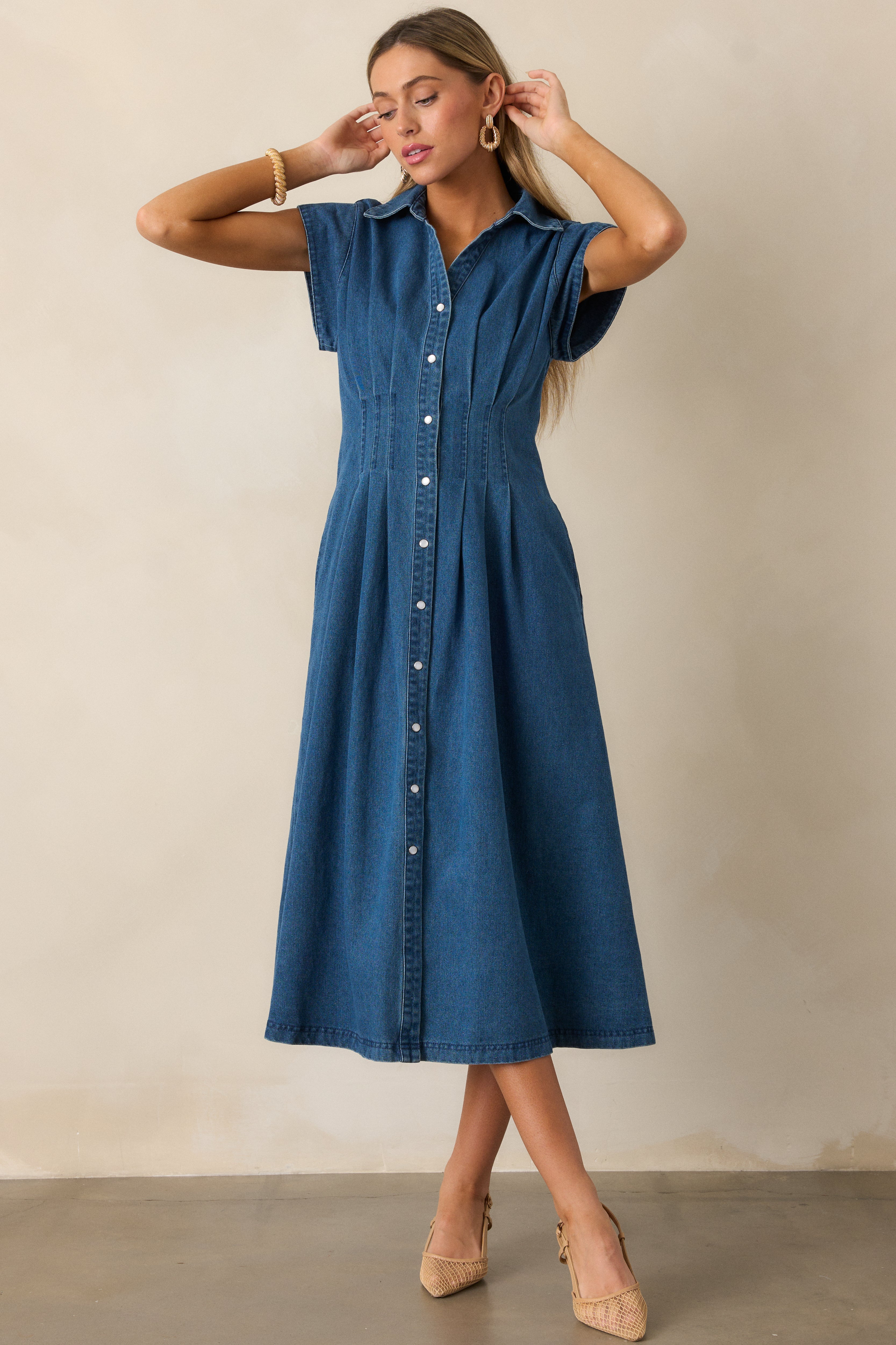 Light wash dress showcasing a pleated waist, cap sleeves, and functional pockets, with a full view of the button-down front design.