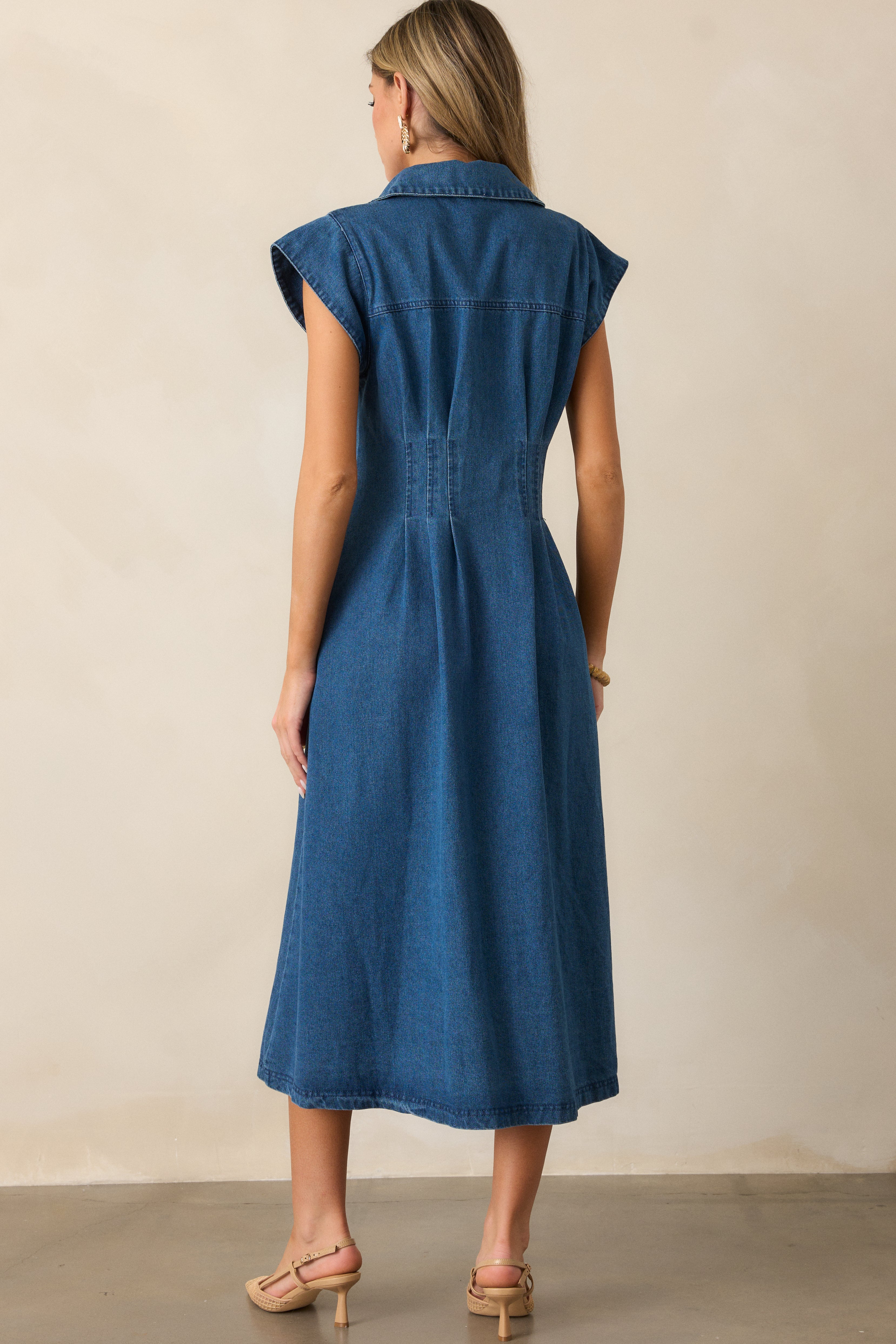 Back view of the light wash dress showing its pleated waist design and cap sleeve details.