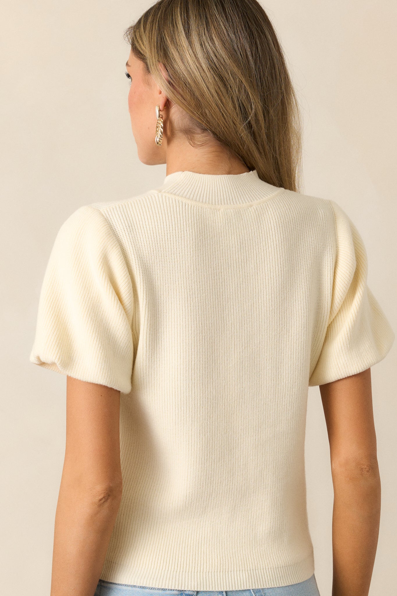  The back view of the ivory top, showcasing the relaxed fit, simple lines, and cozy knit material that defines its effortless style.