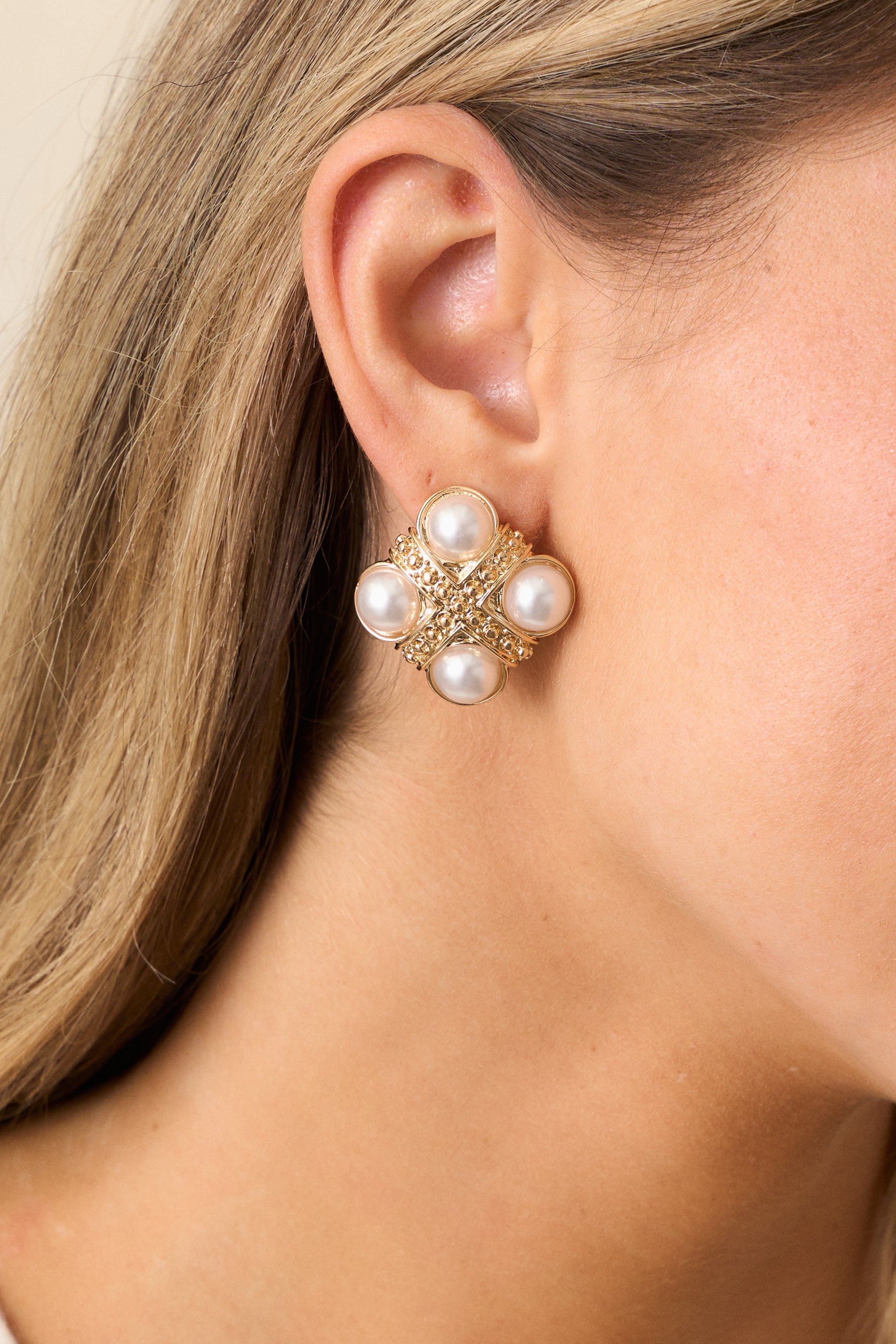 Close-up of the gold and ivory earrings highlighting the crisscross gold beading, faux pearls, and polished gold hardware.