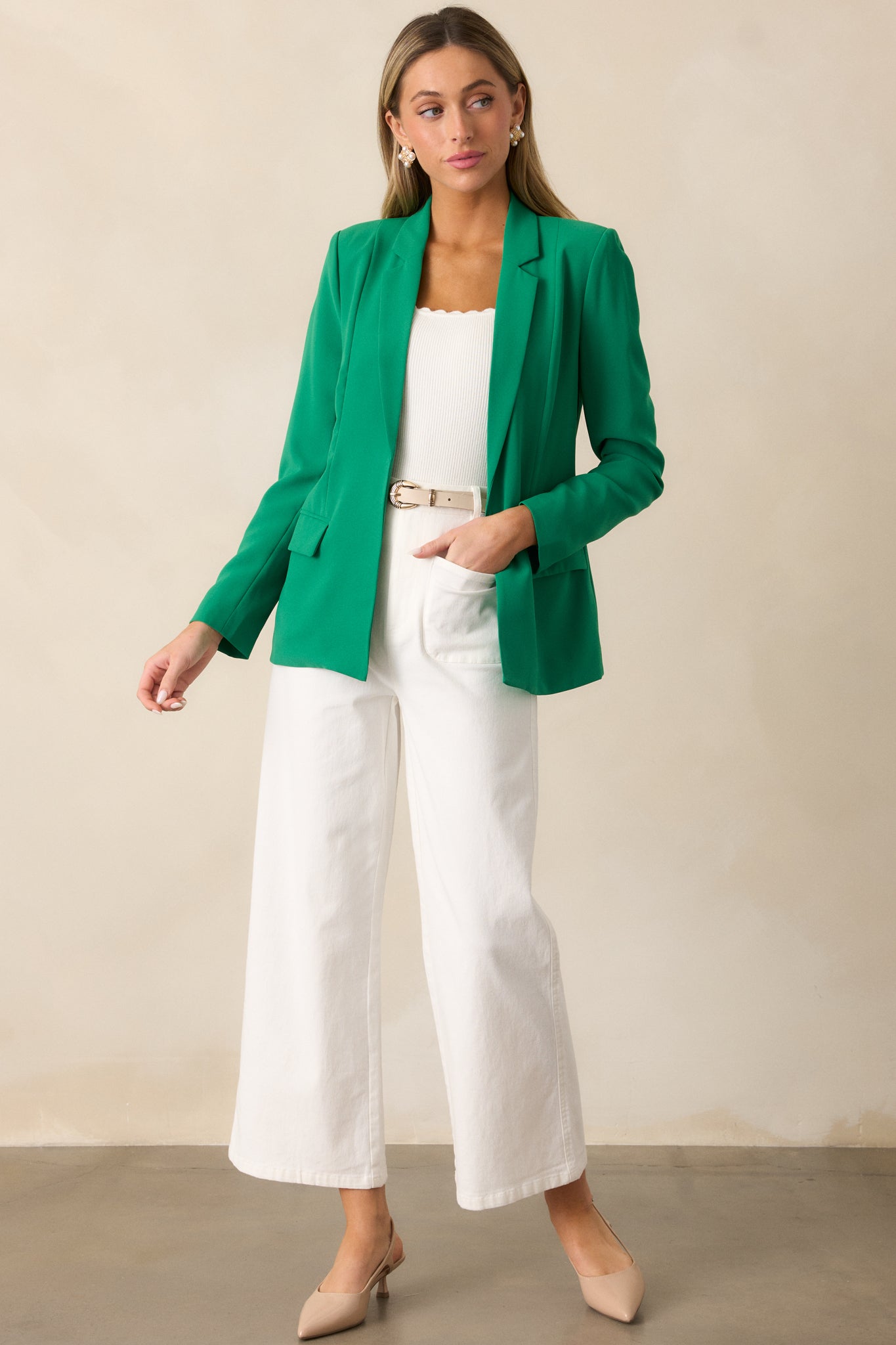 Green blazer with shoulder padding, a notched lapel collar, and a sleek, open-front design, complemented by long sleeves and functional pockets.