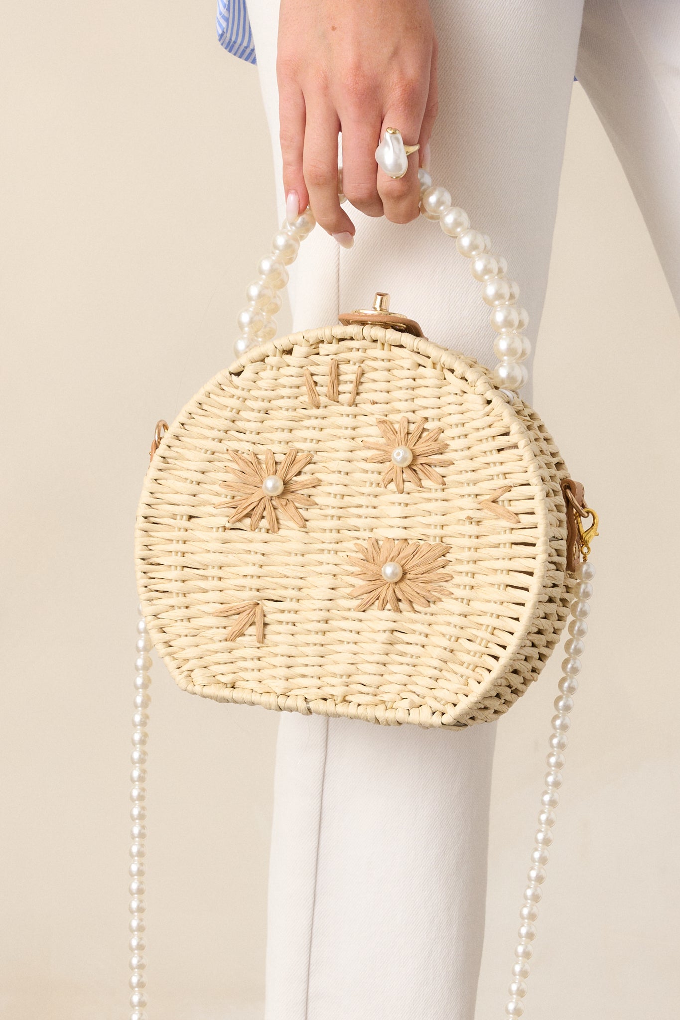 Detail of the large faux ivory pearl beaded handles and the optional ivory faux pearl shoulder strap on the circular handbag.