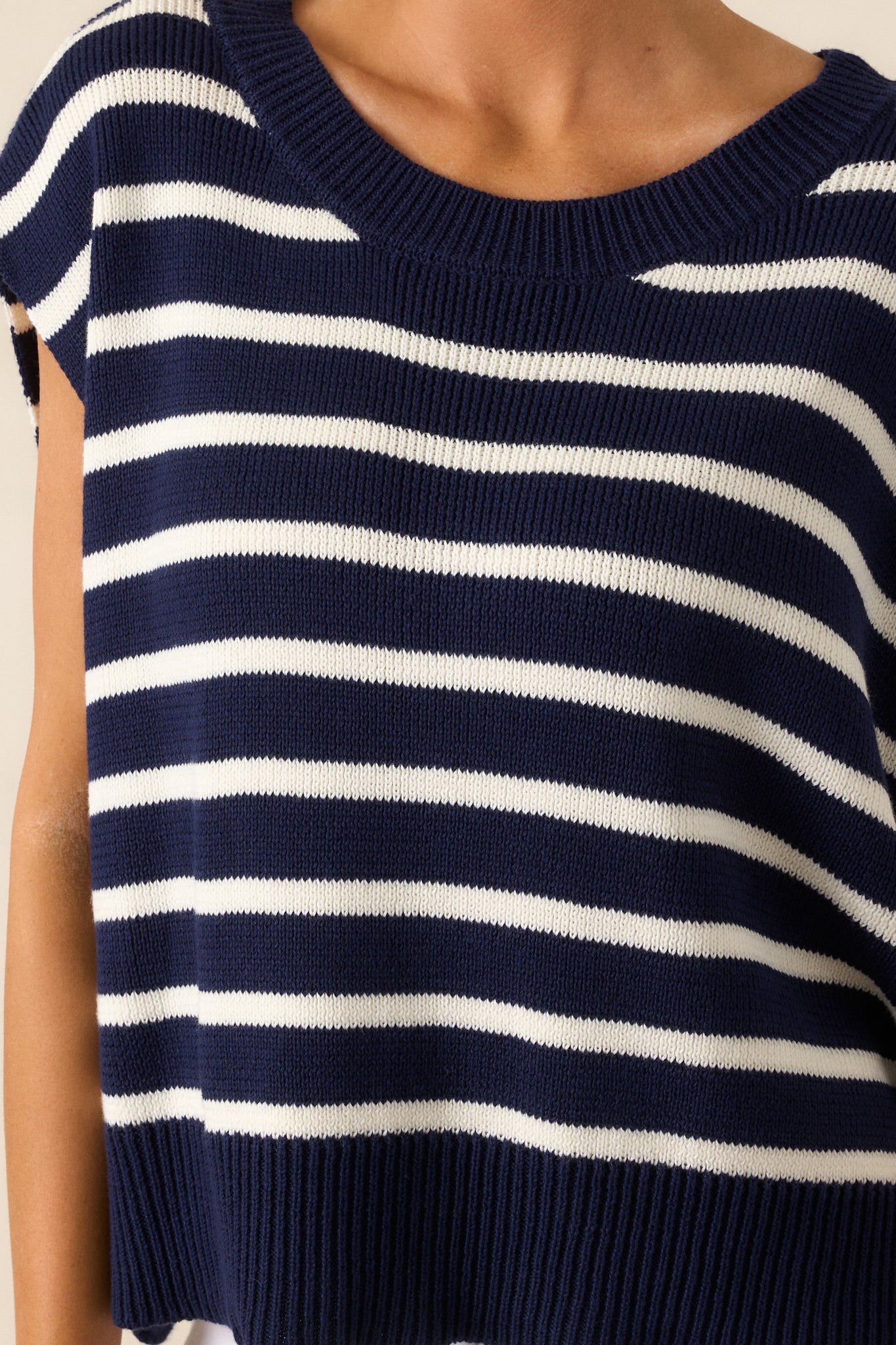 Close-up of the ribbed crew neckline and fine horizontal stripe detailing on the navy sweater top.
