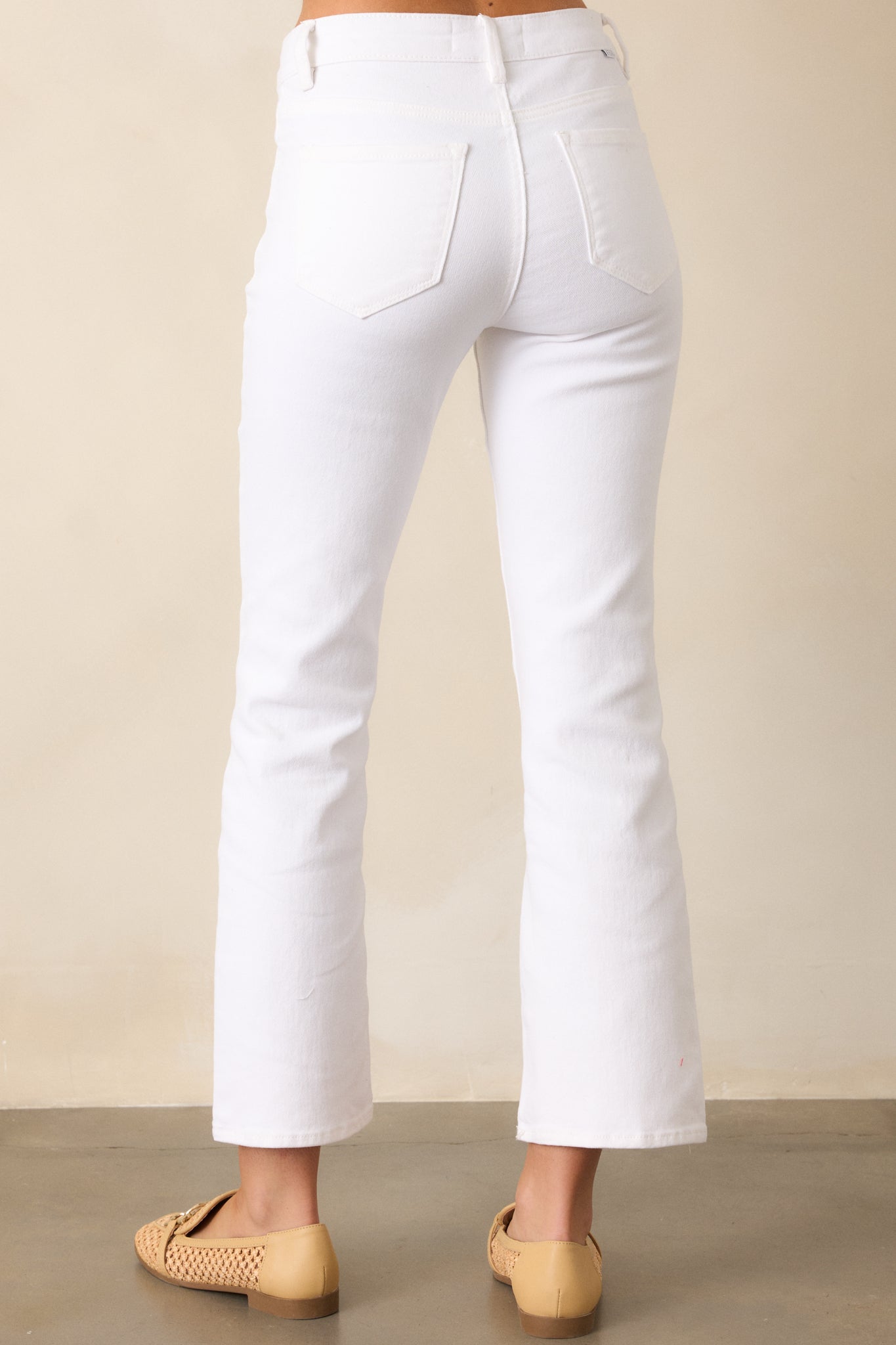 The white jeans from the back, emphasizing the straight-leg cut, functional back pockets, and high-waisted silhouette for a streamlined and polished look.