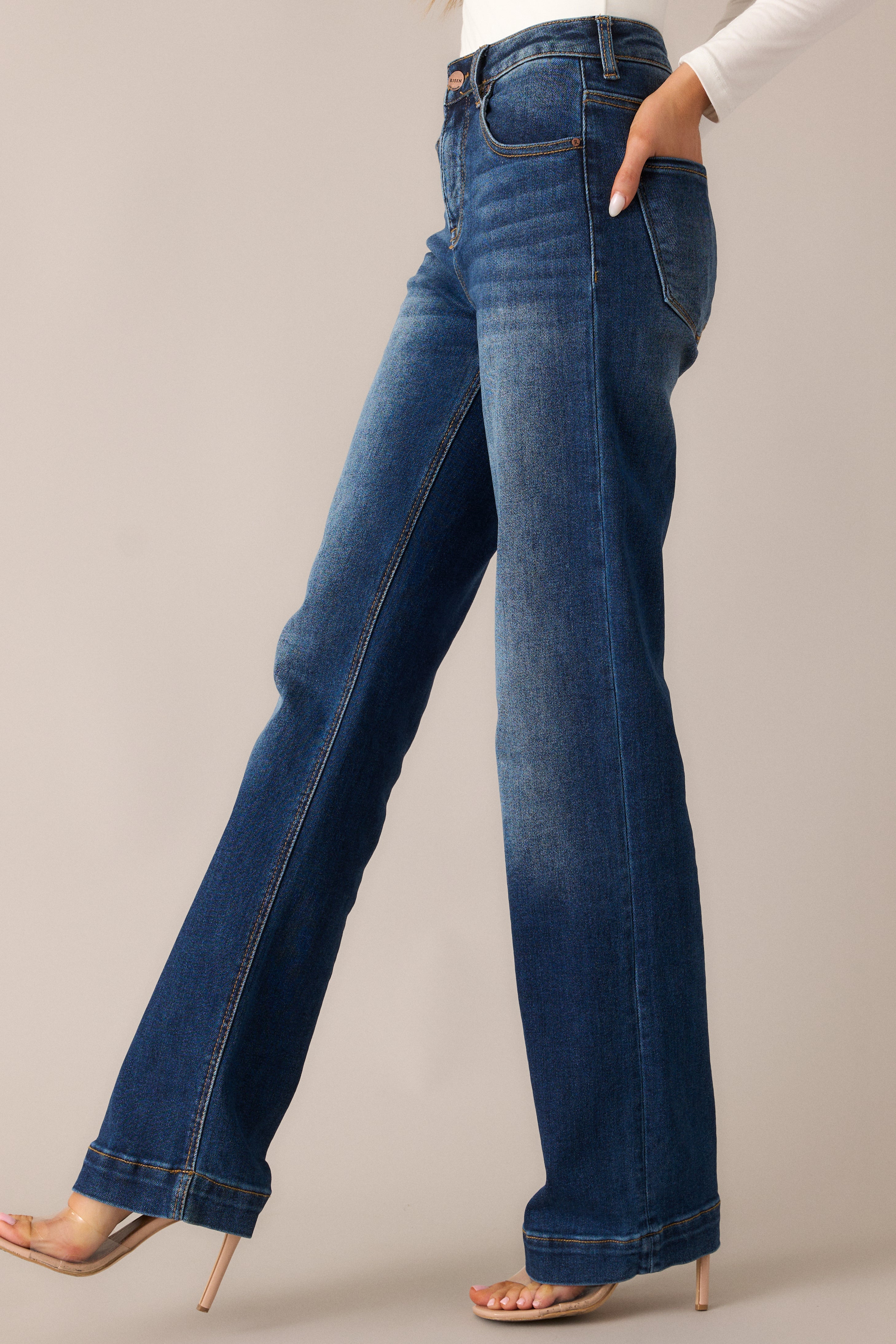  Timeless dark wash jeans featuring a high waist, functional pockets, and a straight leg silhouette, with faded thighs and knees that add a touch of character to the dark wash design.