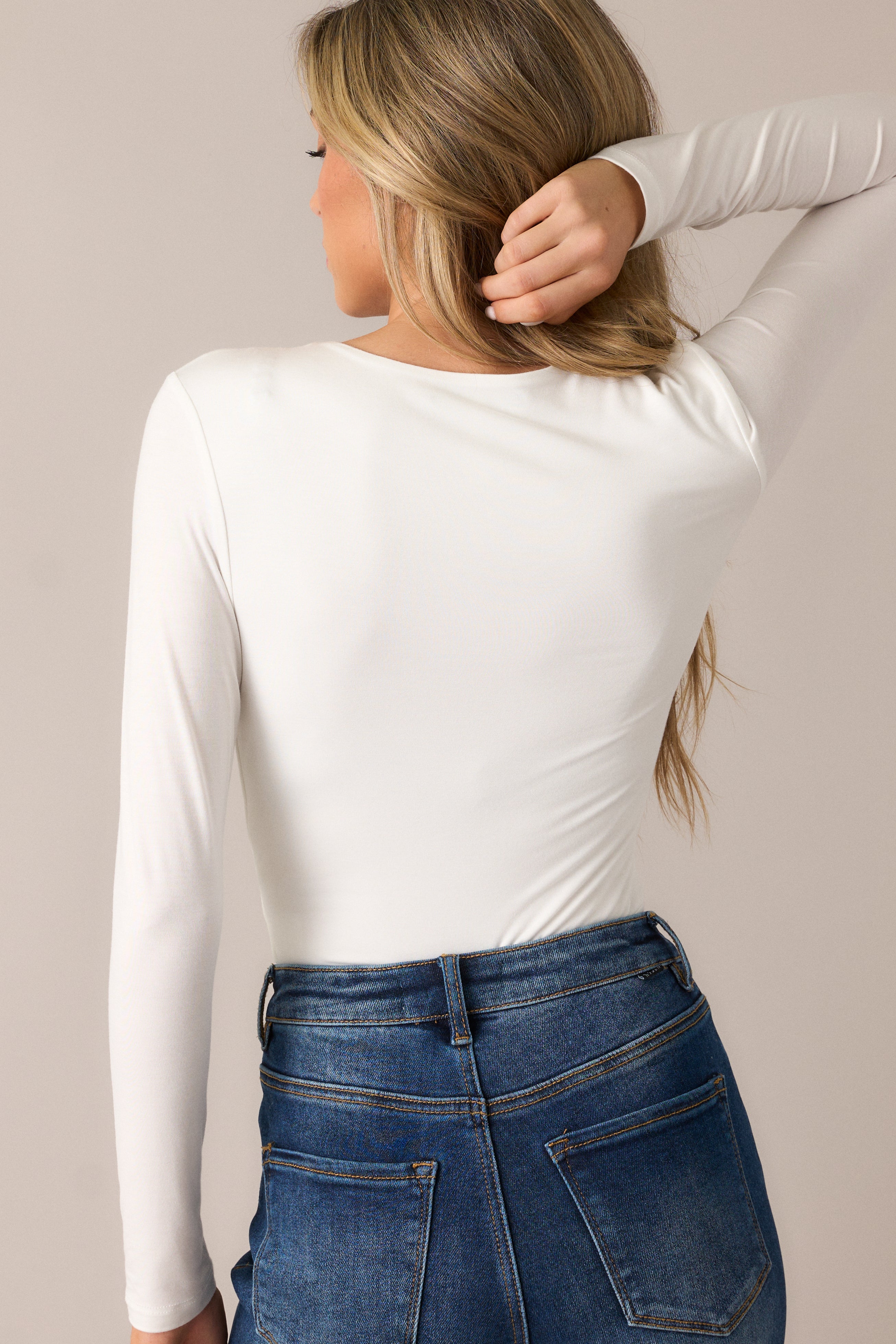 The bodysuit from behind, emphasizing the smooth fabric and the long sleeve design, with attention to the sleek, snap button finish.