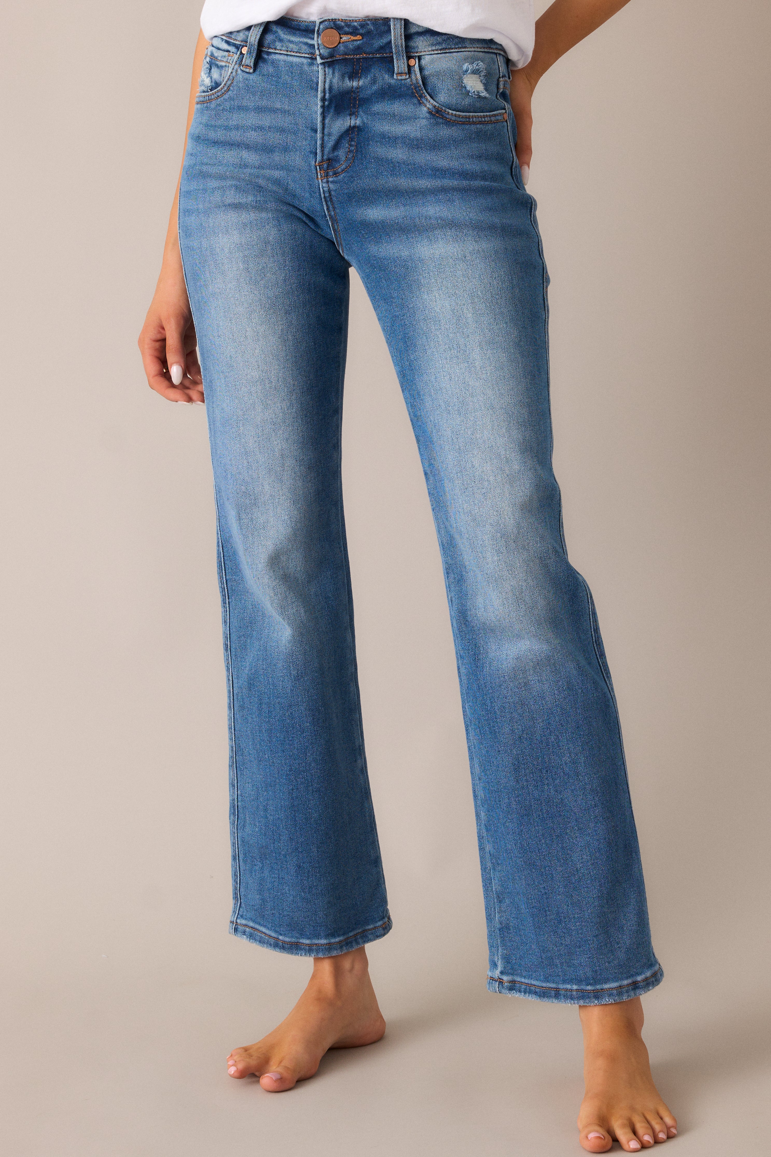 Medium wash jeans with a high-rise fit and straight-leg cut, shown styled with a slightly distressed finish and functional front and back pockets.