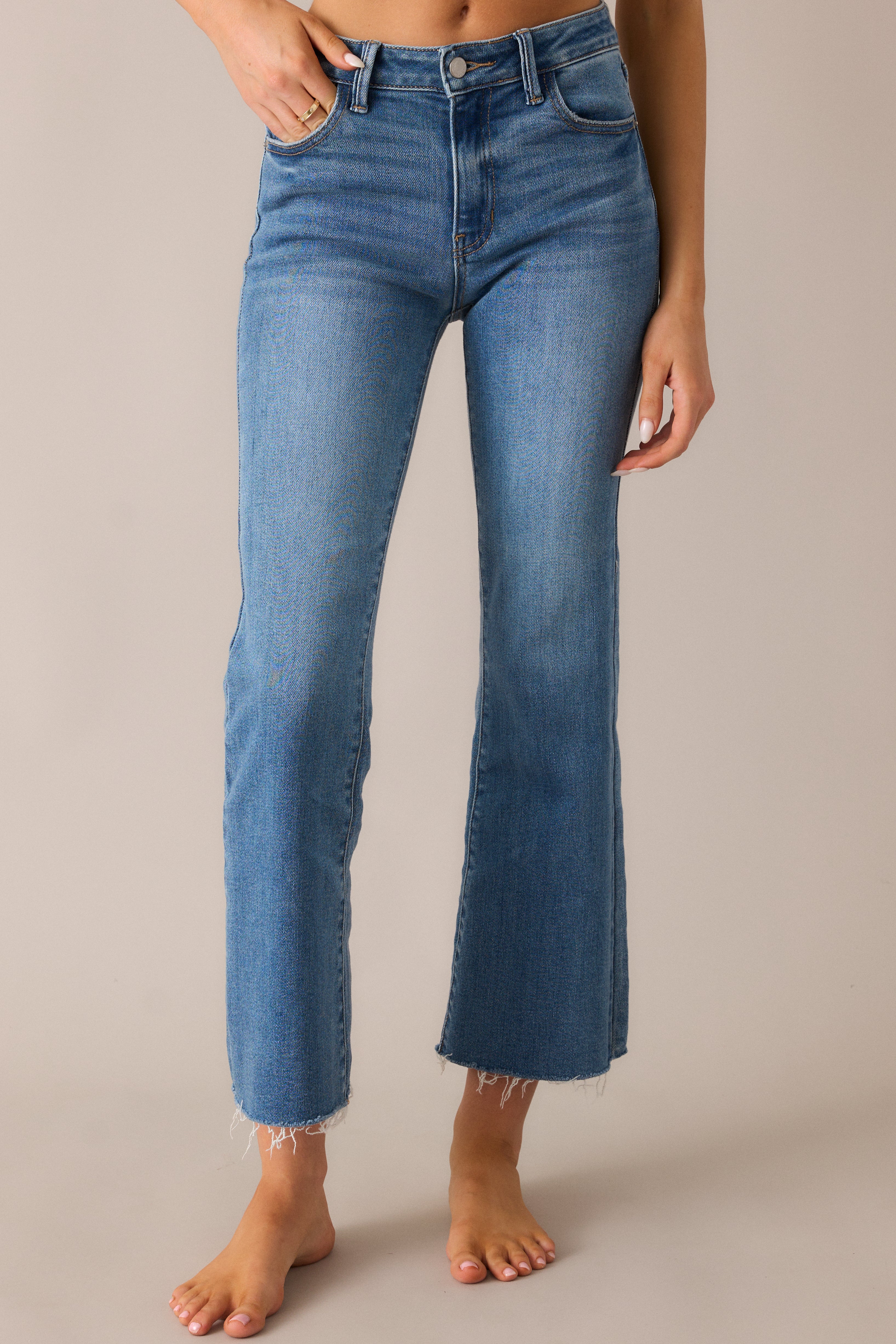 Trendy medium-wash jeans with a classic button-zipper closure, functional belt loops, and a flare leg design, creating a stylish and flattering silhouette with a cropped raw hem.