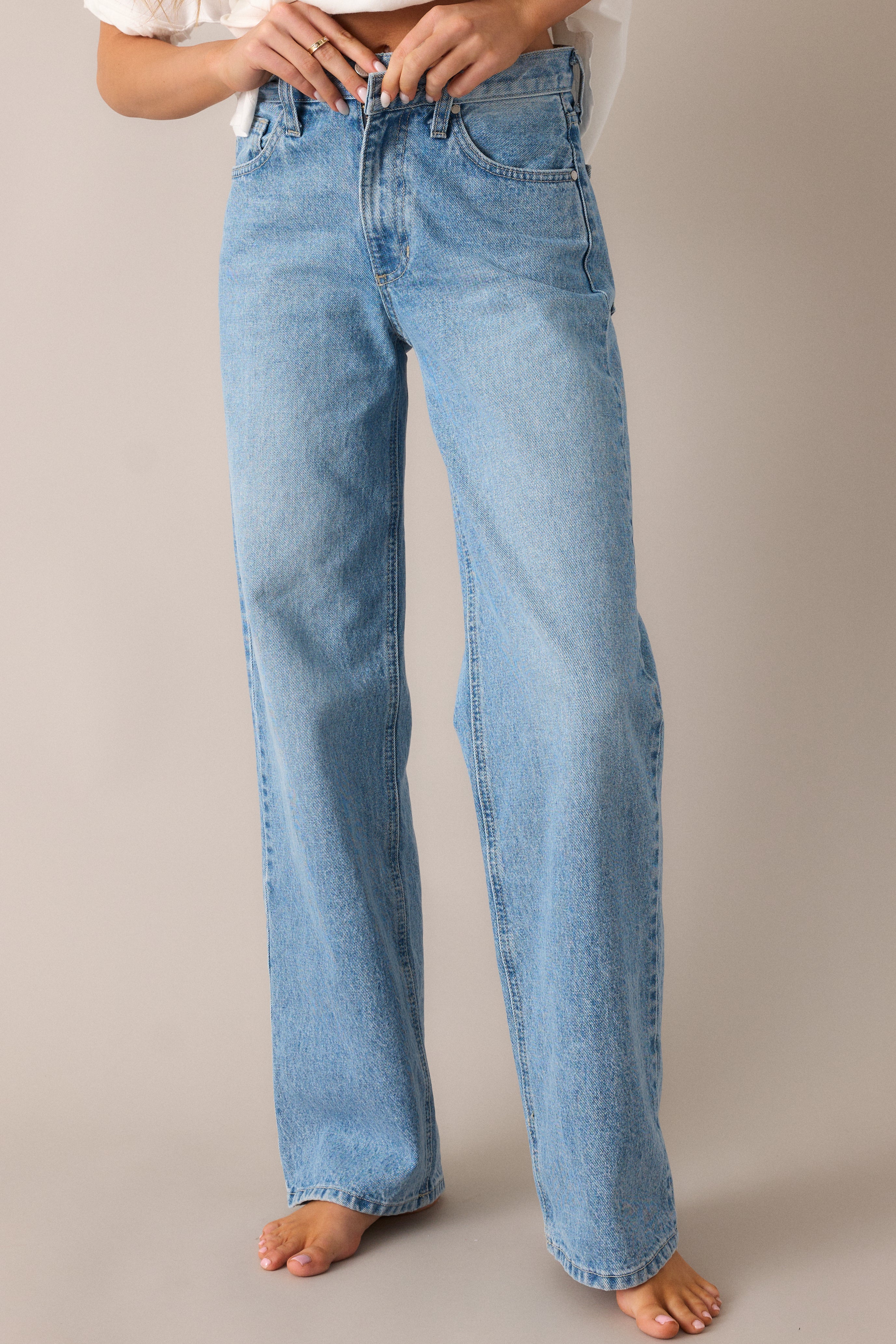 Close-up of the relaxed fit and high-waist design, showcasing the smooth, straight-leg cut and the button & zip closure that adds a classic touch to these light wash jeans.