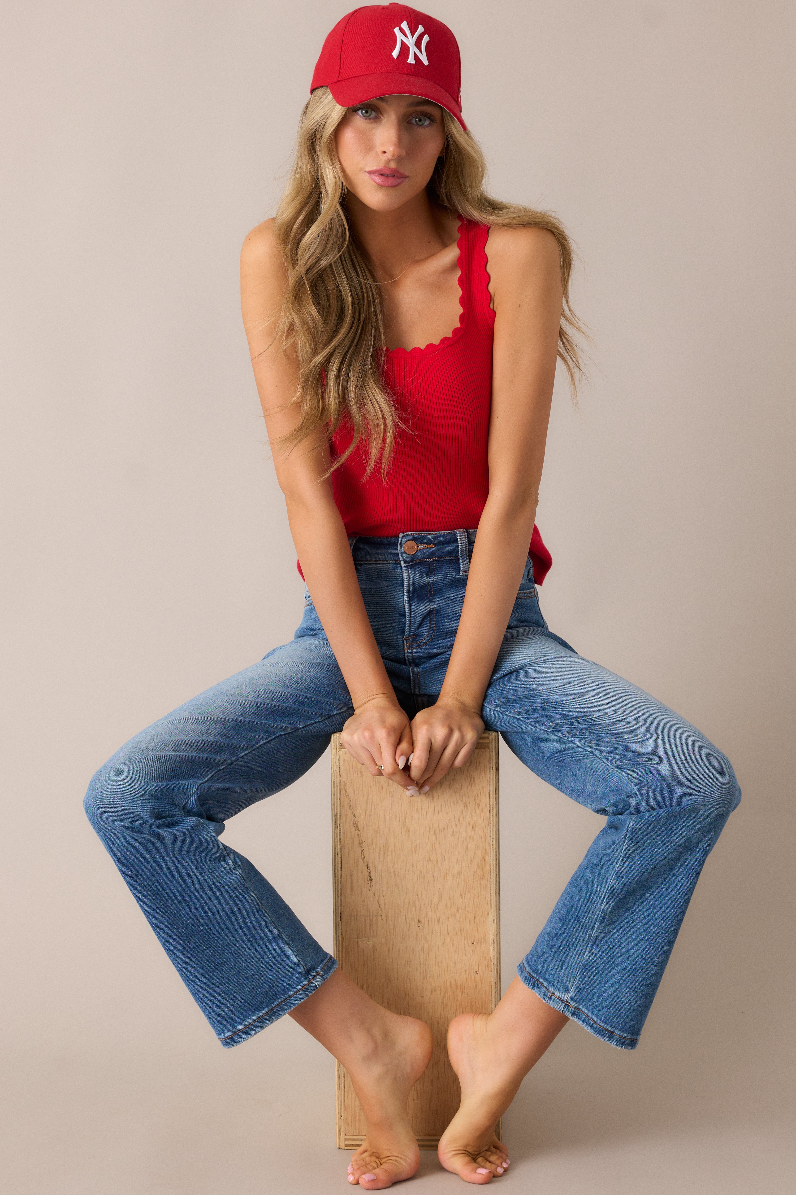 Chic and fitted red tank featuring a square neckline, ribbed texture, and a scalloped hem, with a sleeveless cut perfect for layering or wearing on its own.