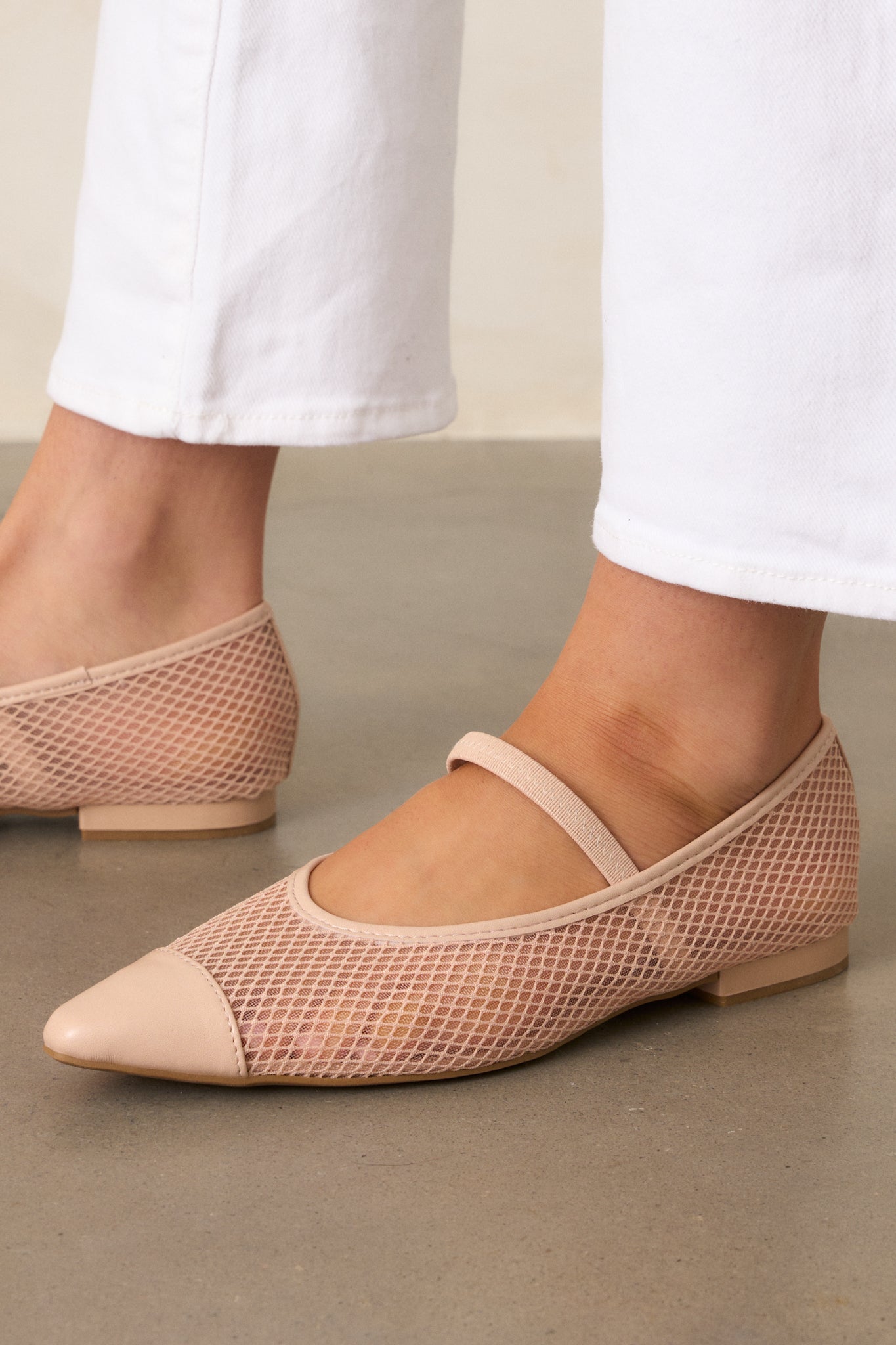 A close-up view of the beige mesh flats, highlighting the solid beige pointed toe, the mesh fishnet sides, and the small beige heel, with the elastic foot strap and beige trim visible.