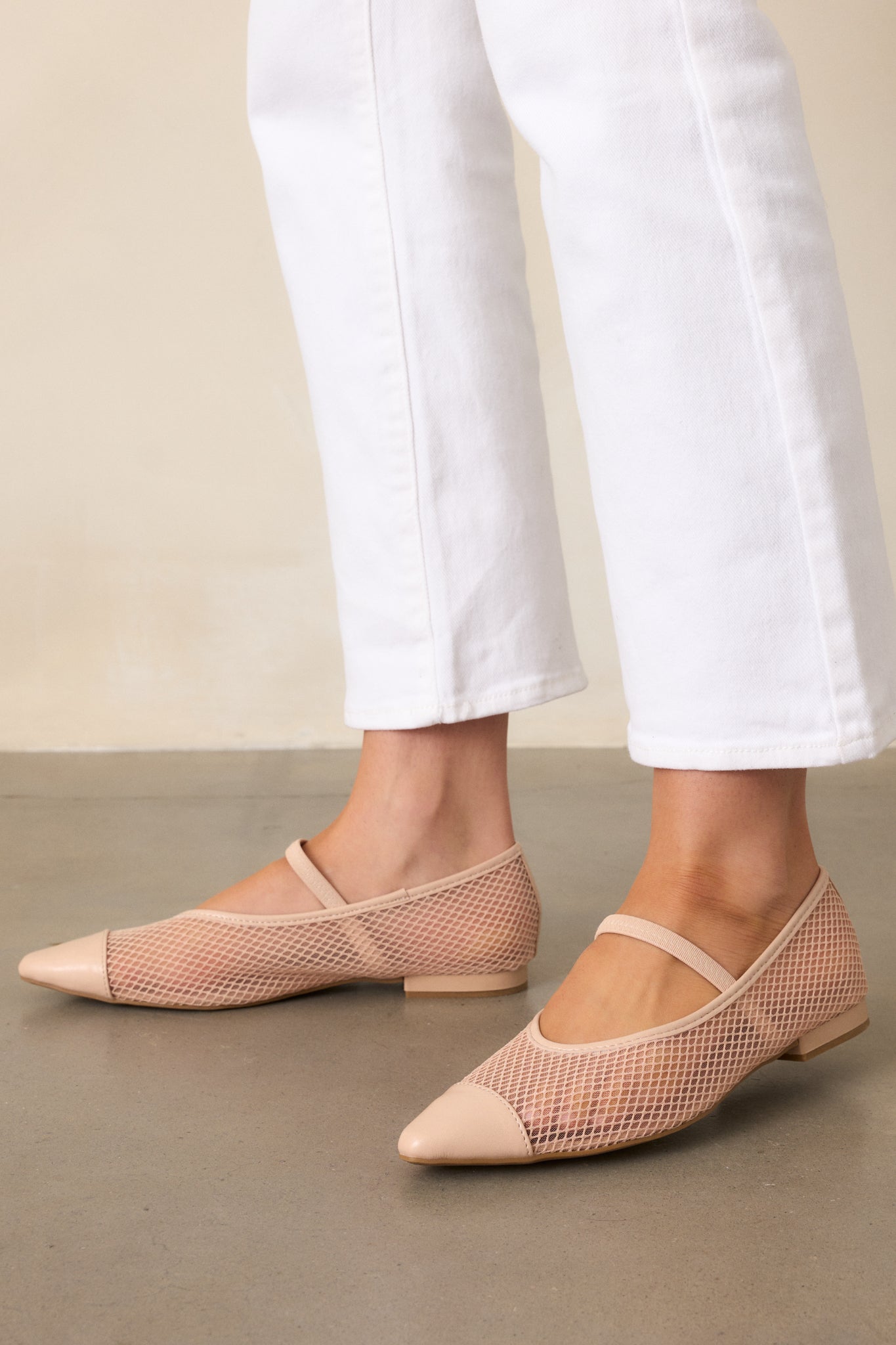 A cropped shot of the beige mesh flats, focusing on the mesh fishnet sides, solid beige pointed toe, and the elastic foot strap, with the small beige heel and extra cushioning in the sole subtly visible.