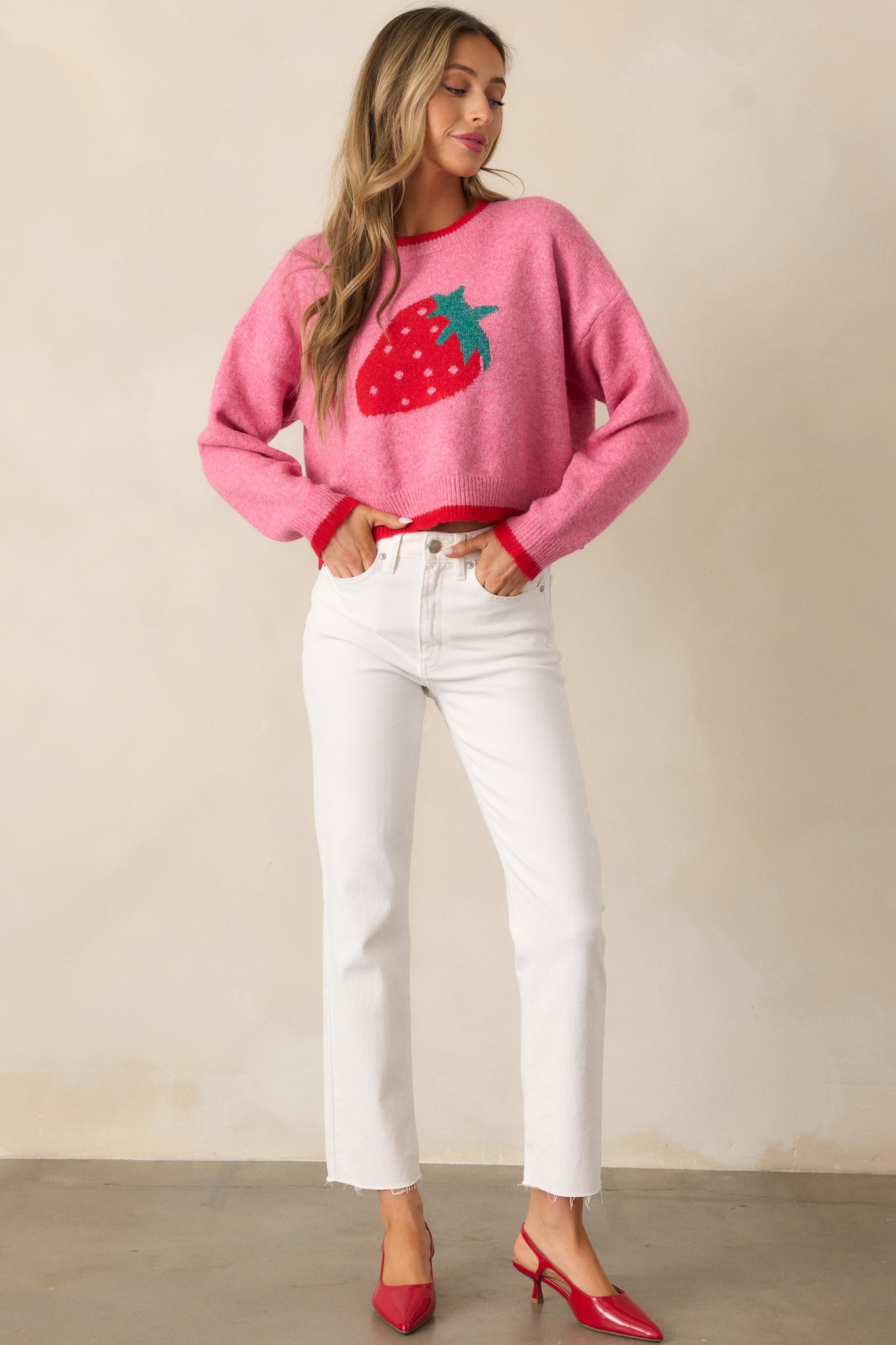 A delightful pink sweater featuring juicy strawberry patterns, bright red trim, and a fun, cropped silhouette.
