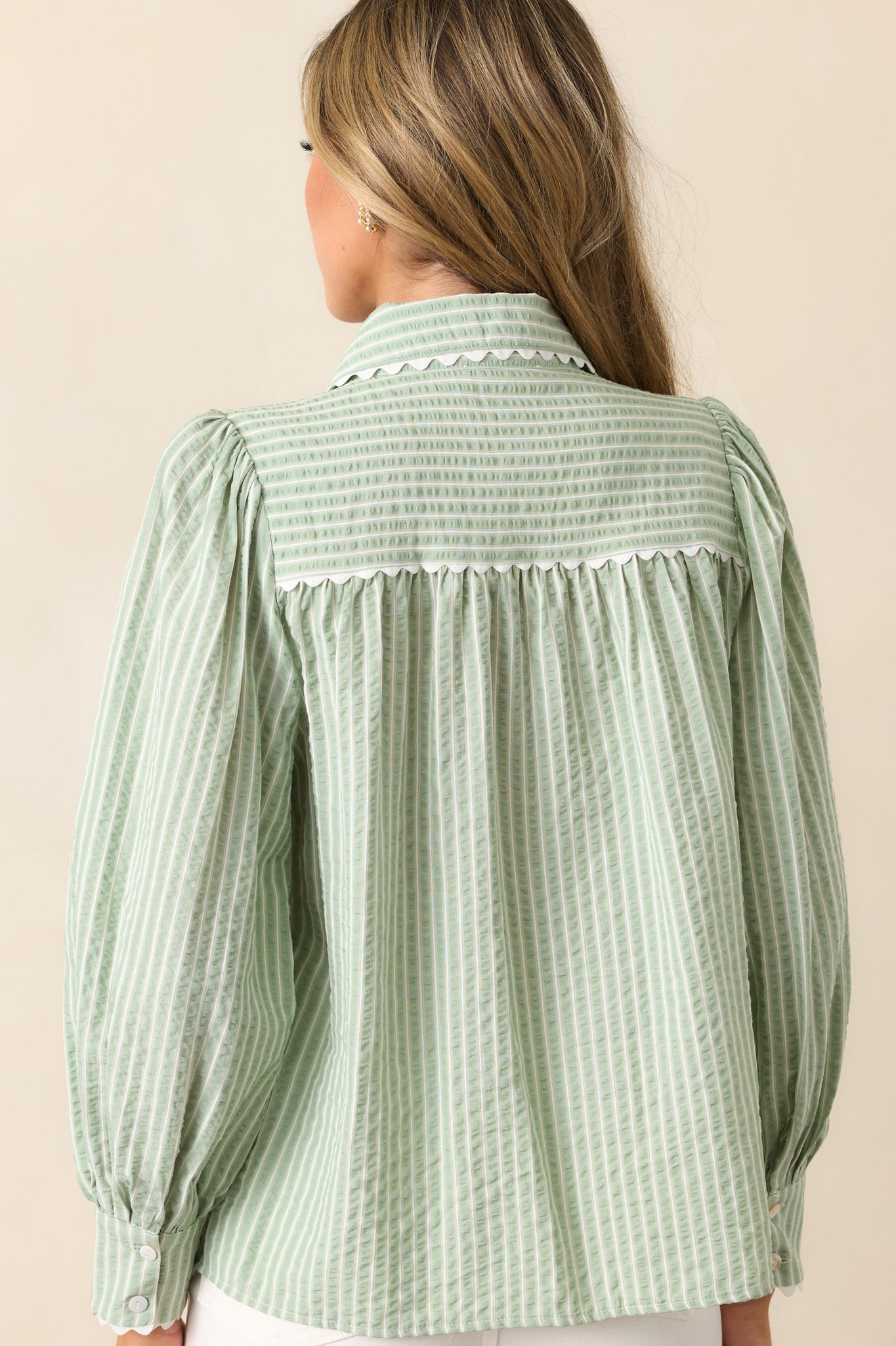 The back of this sage blouse showcases its stripe print and relaxed drape for a timeless, effortless style.