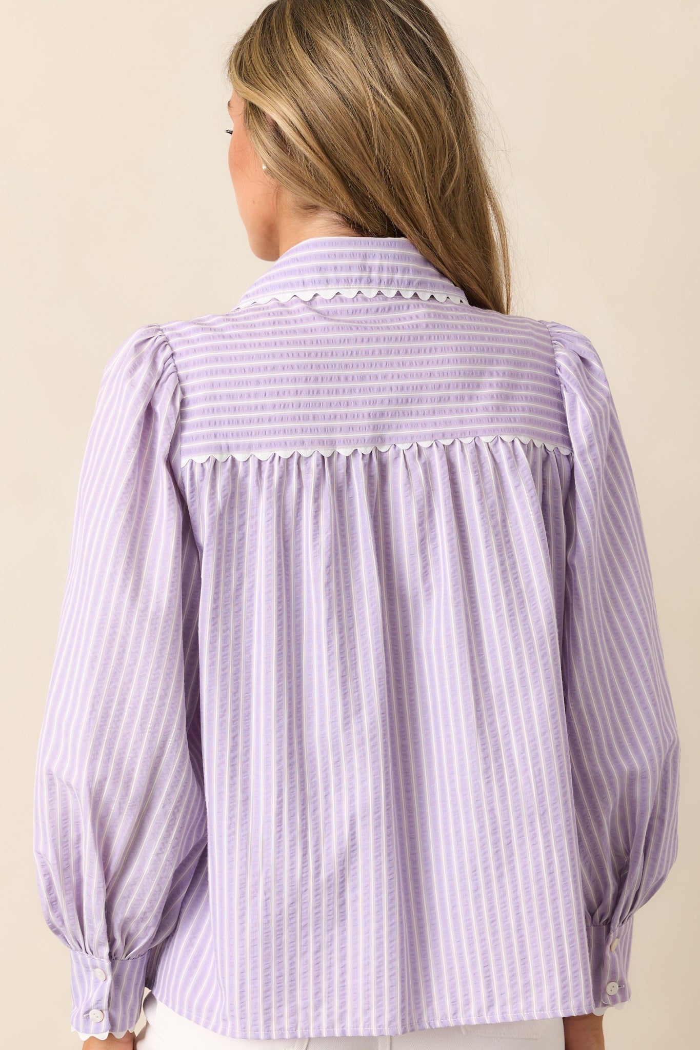 The back of this lavender blouse showcases its stripe print and relaxed drape for a timeless, effortless style.