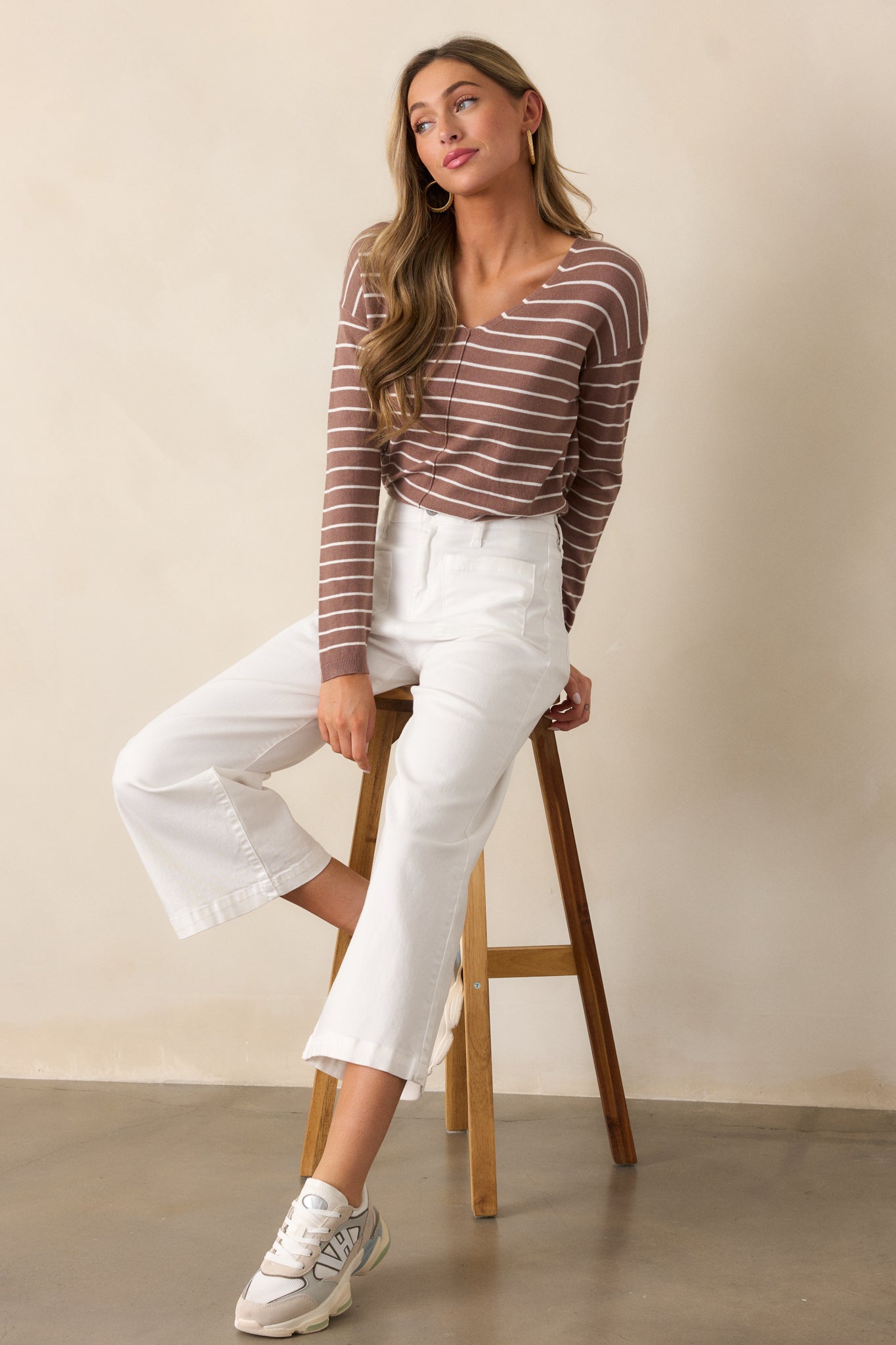 A full-length shot of the light mocha top featuring a v-neckline and long sleeves. The thin white stripes add a subtle, textured pattern across the relaxed fit of the shirt, with front seam detailing visible along the center.