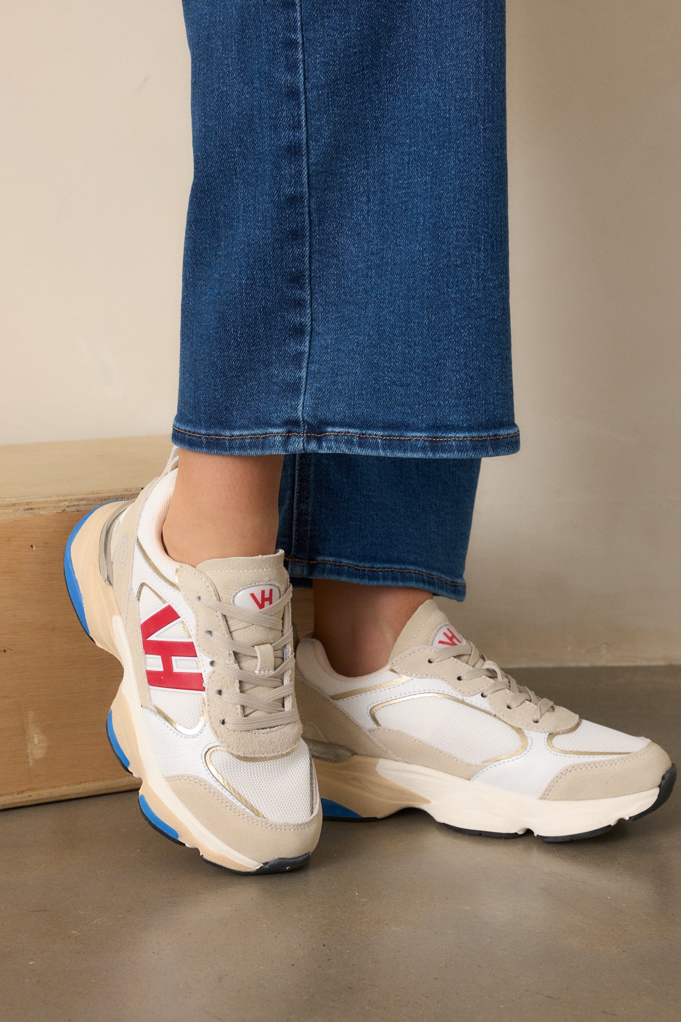 A side view of grey sneakers with beige and grey color blocking, a large red VH symbol, and a thick beige sole with blue accents on the bottom.