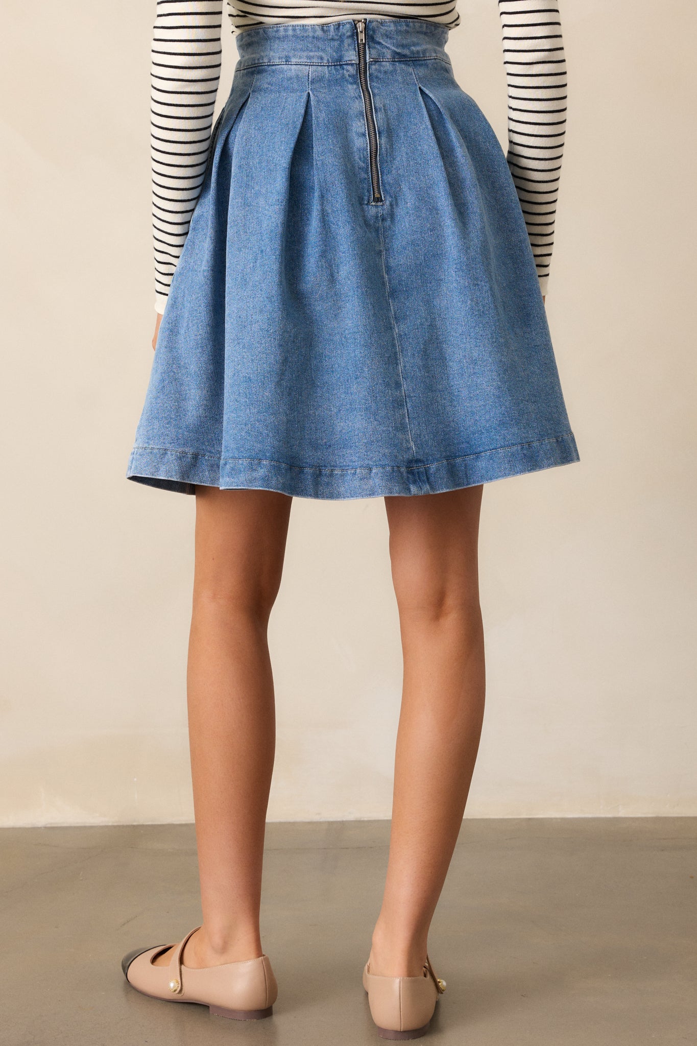 A cropped view of the back zipper closure on the denim skirt, highlighting the craftsmanship and clean finish.