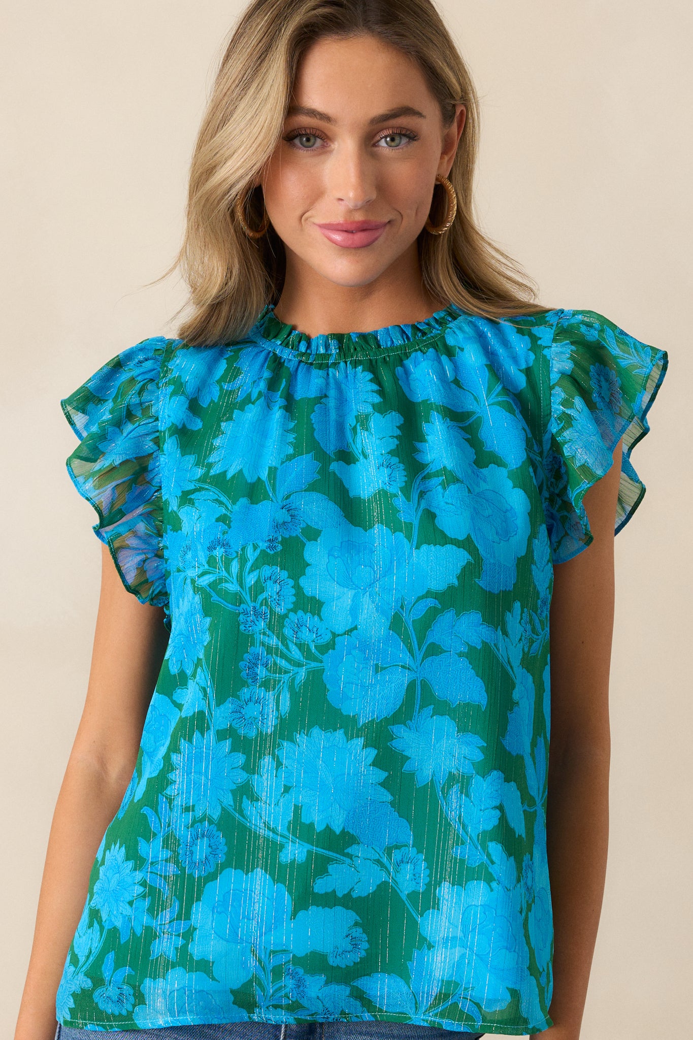 Detailed view of the short flutter sleeves and relaxed fit of the blue blouse.