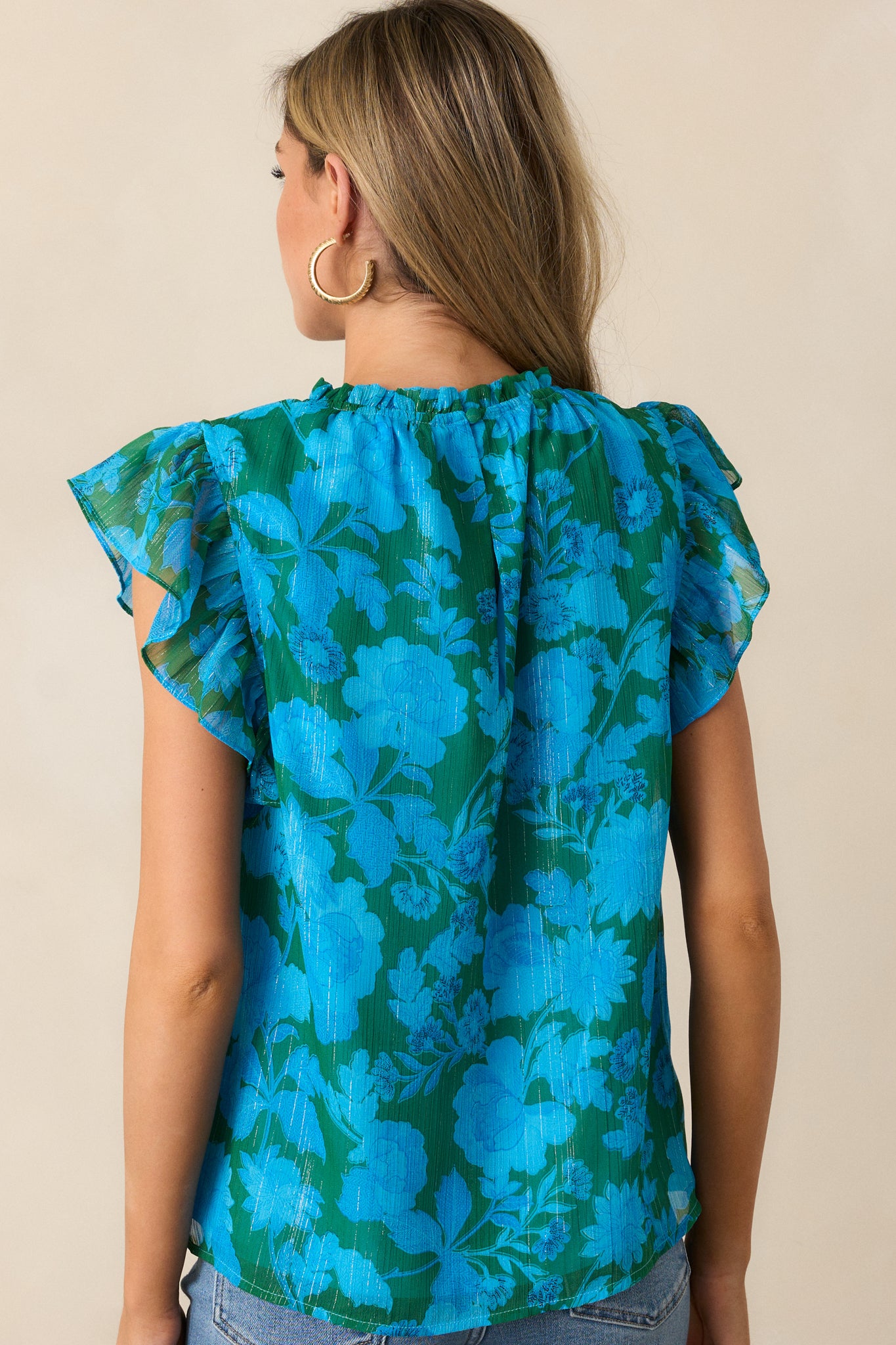 A back view of the blue blouse, showcasing the relaxed fit and short flutter sleeves.