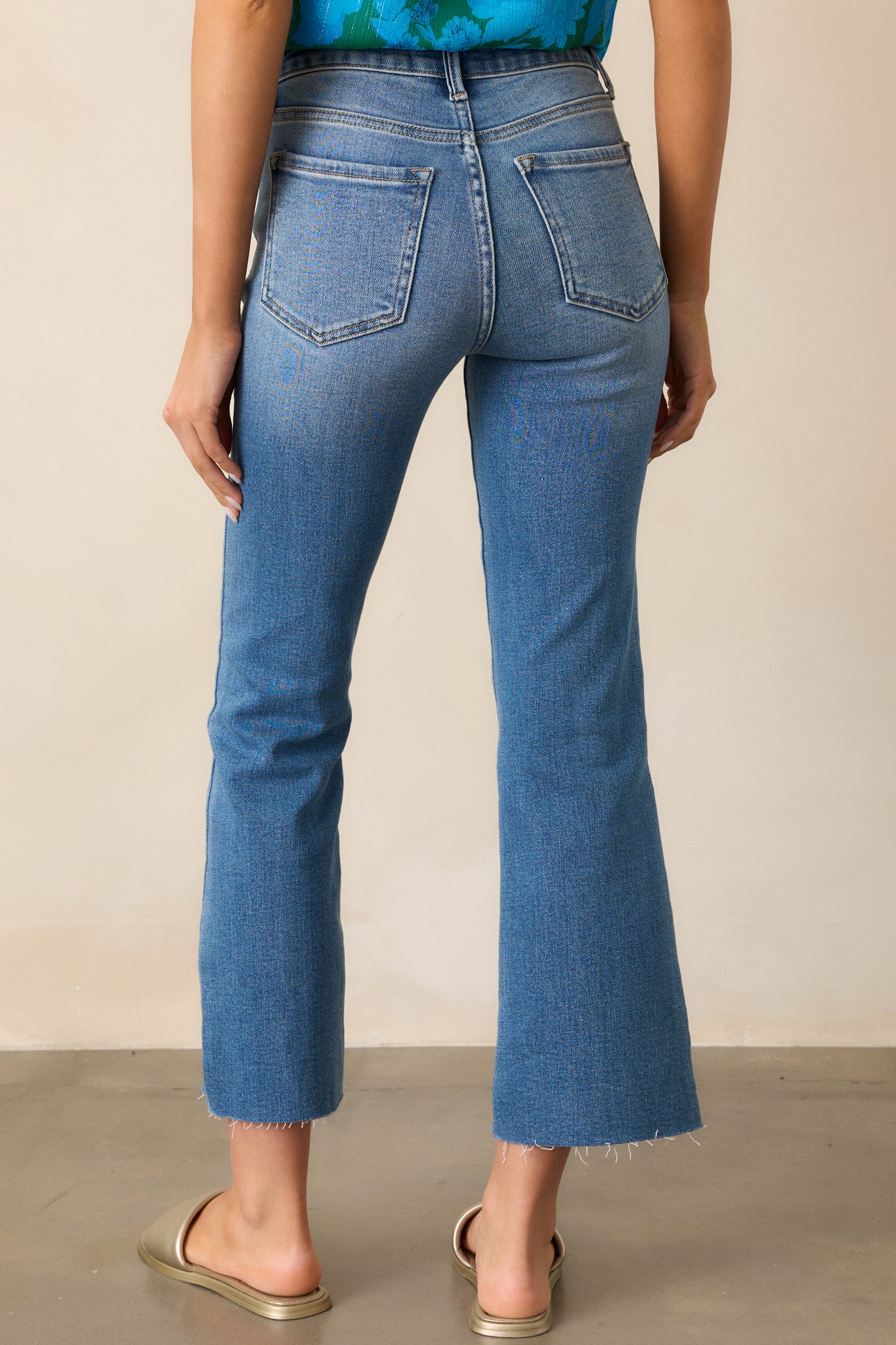 A back view of the medium wash jeans, highlighting the functional back pockets and the flared leg silhouette.