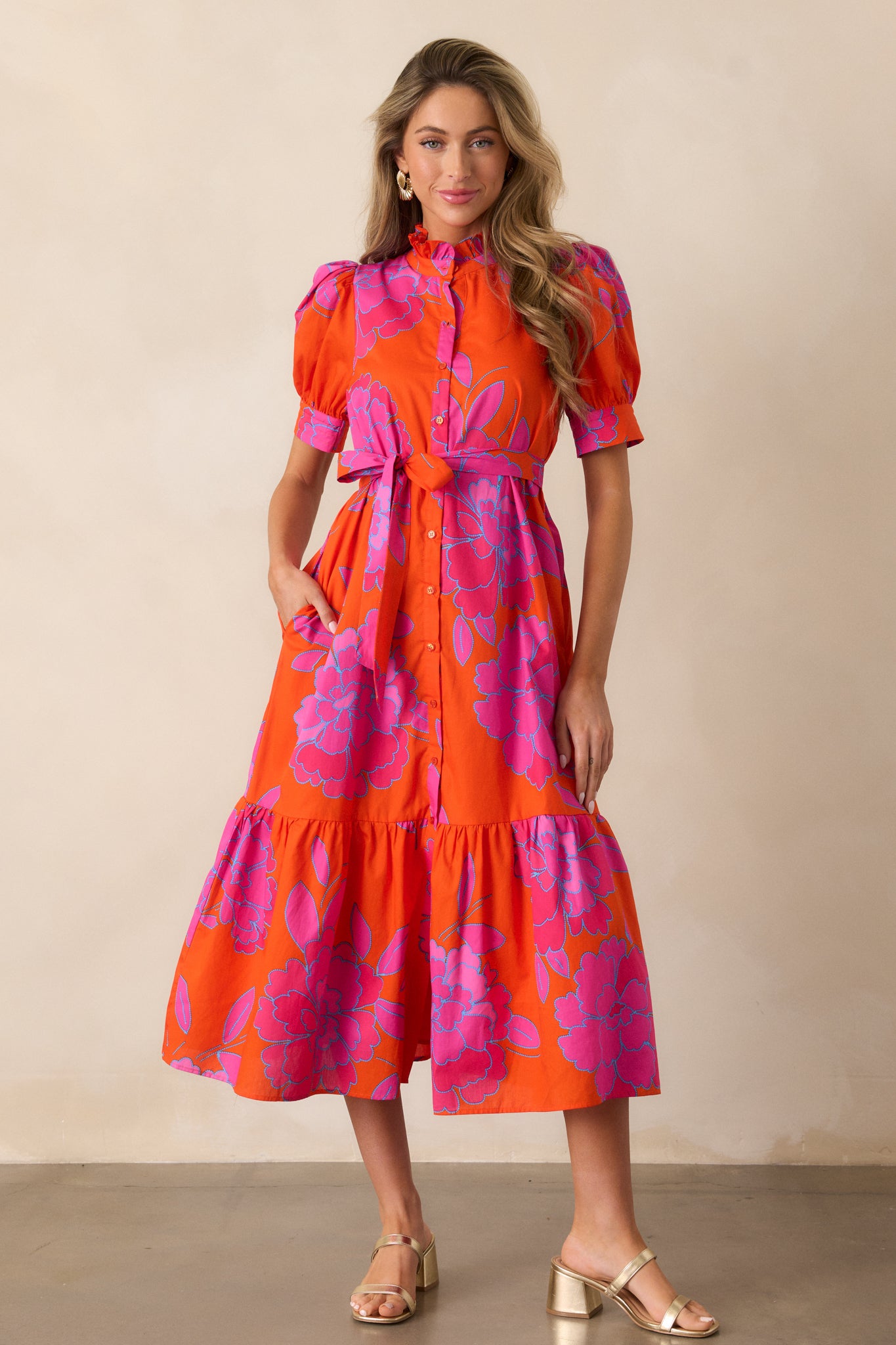  Full-length image of the orange dress, emphasizing the button front design and tiered skirt that creates a flowing silhouette.