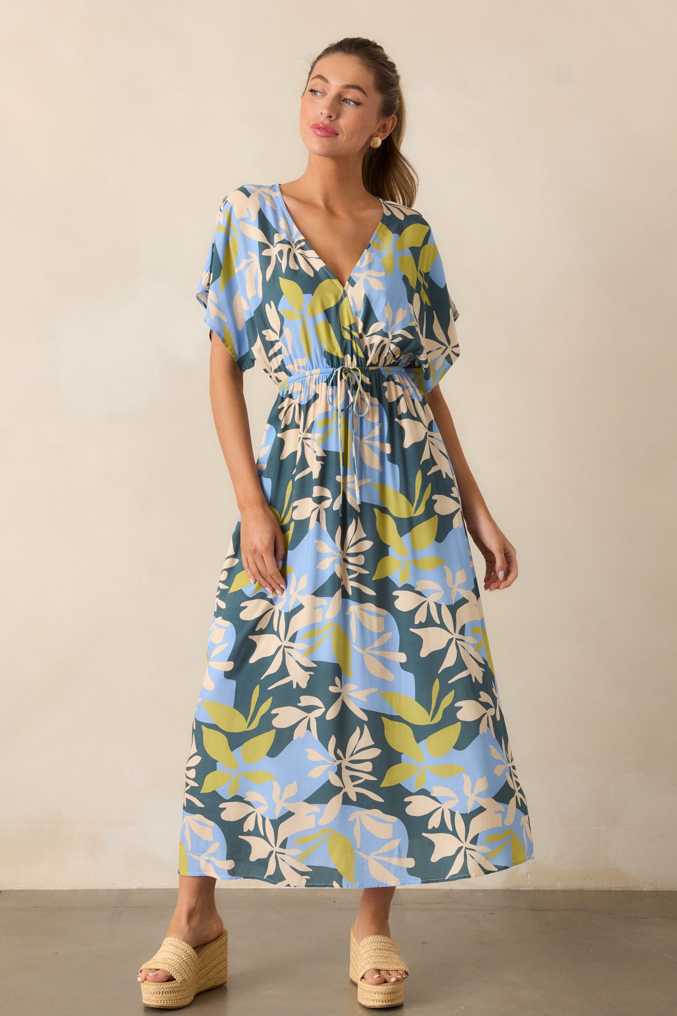 The green dress in a full-length shot, featuring its garden pattern, short kimono-style sleeves, and flowing midi silhouette.