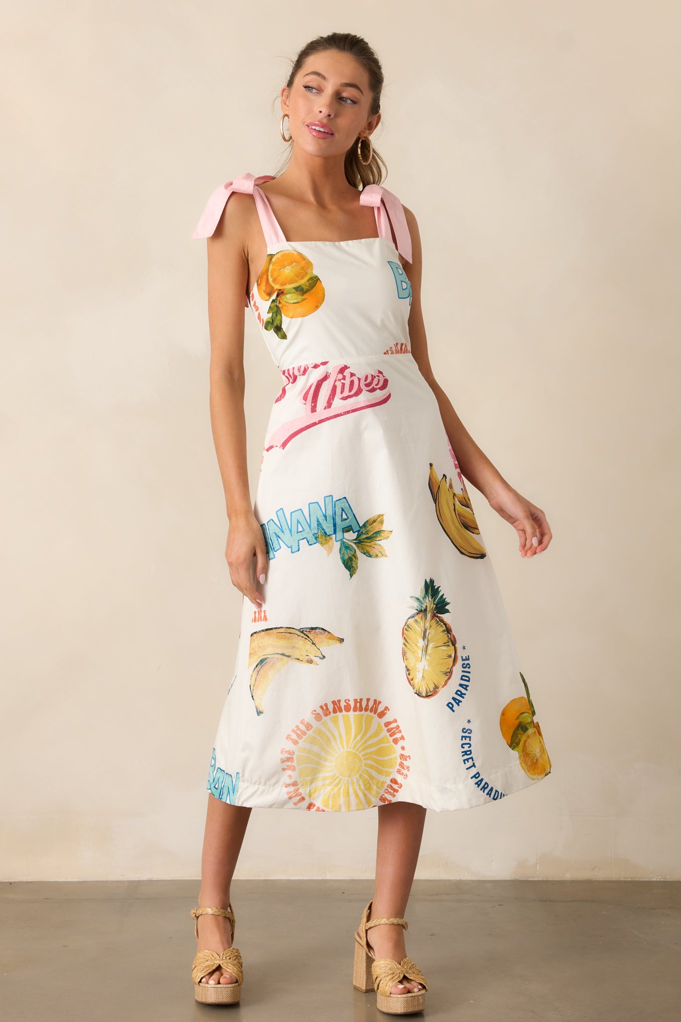 A closer look at the square neckline and colorful tropical fruit print on the dress.