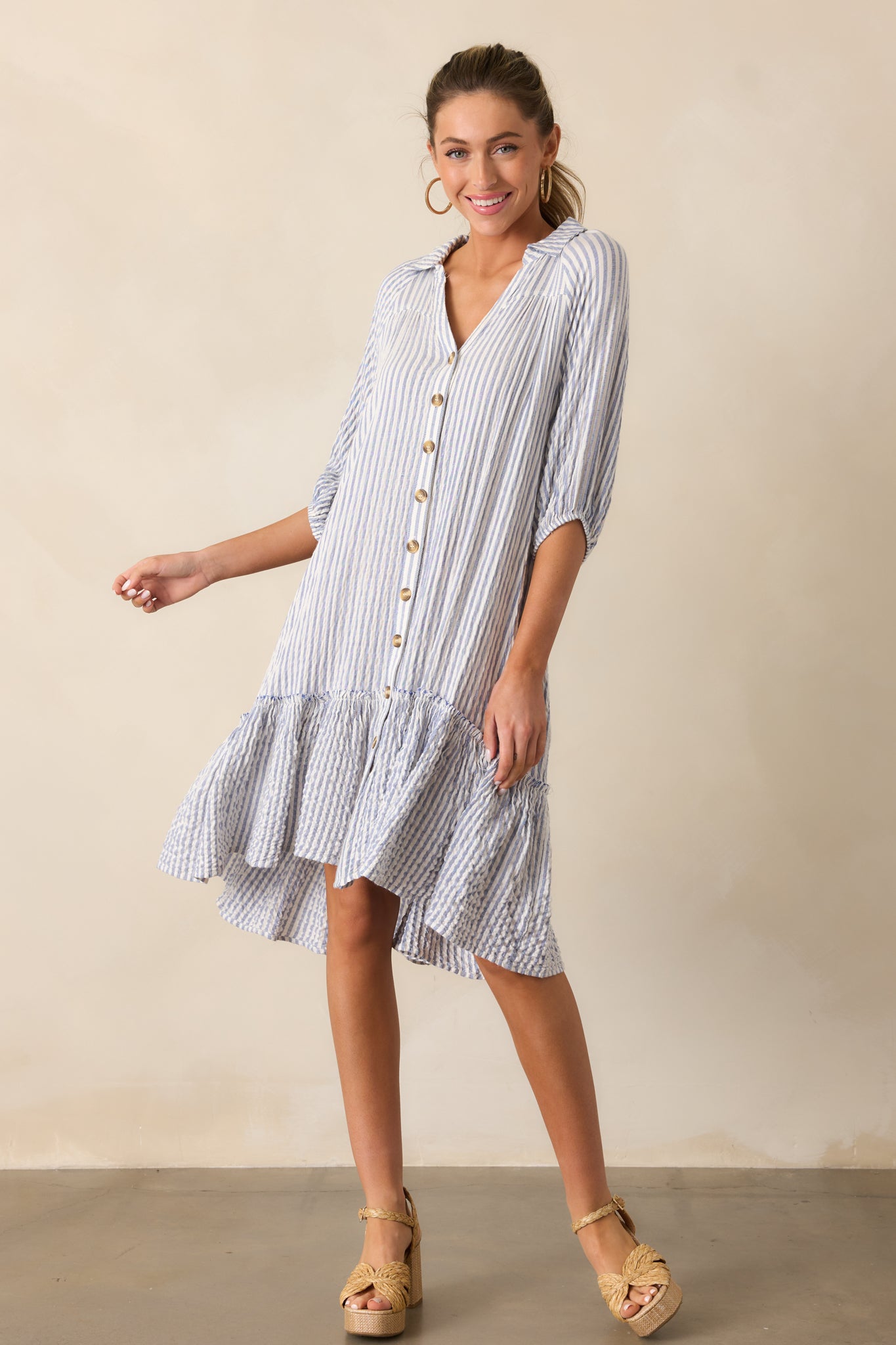 A full view of the light blue mini dress showcasing its collared neckline, button front, and vertical stripes.