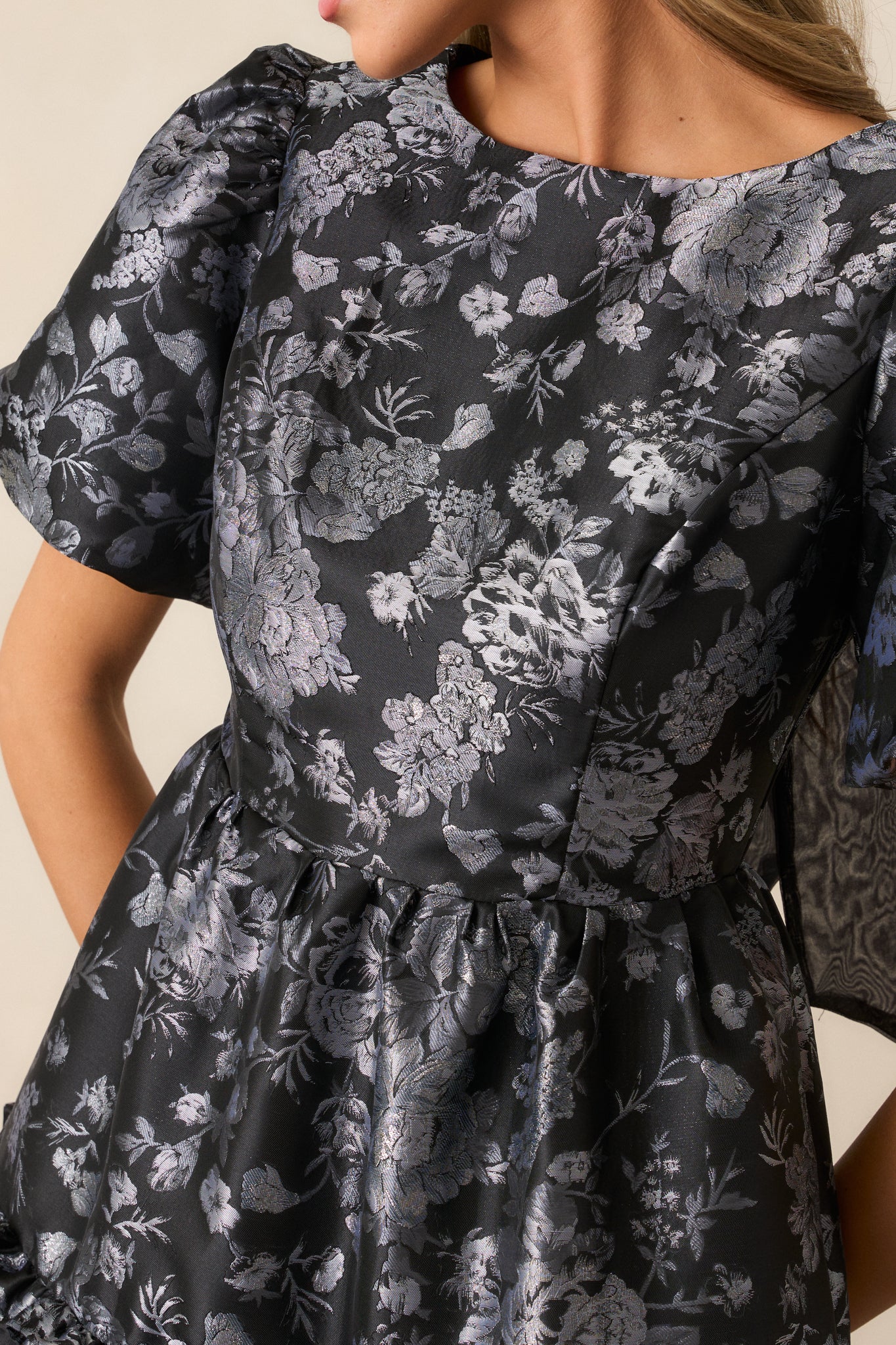 A close-up of the shiny silver floral pattern, capturing its intricate detailing against the black fabric and the soft texture of the ruffles.