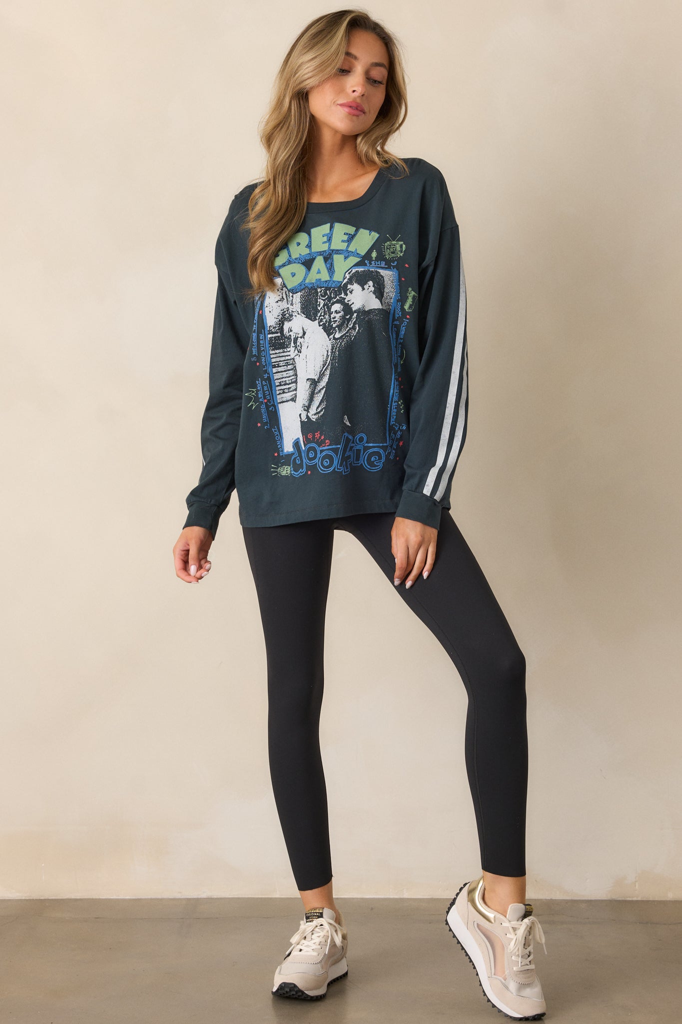 A vintage black tee with long sleeves and a bold Green Day graphic is displayed in a full-body side view, emphasizing the relaxed fit.