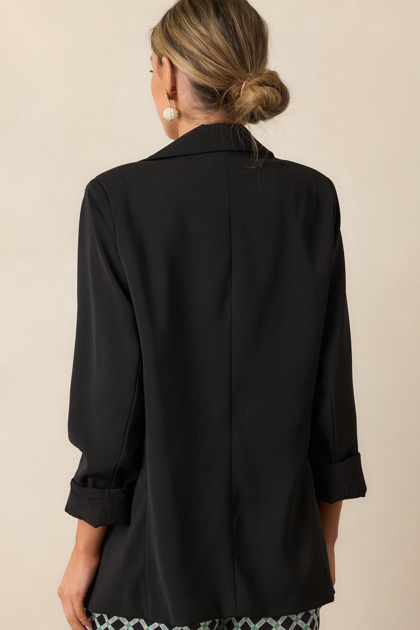 Back view of the black blazer, highlighting the tailored fit and smooth lines across the shoulders and back panel.