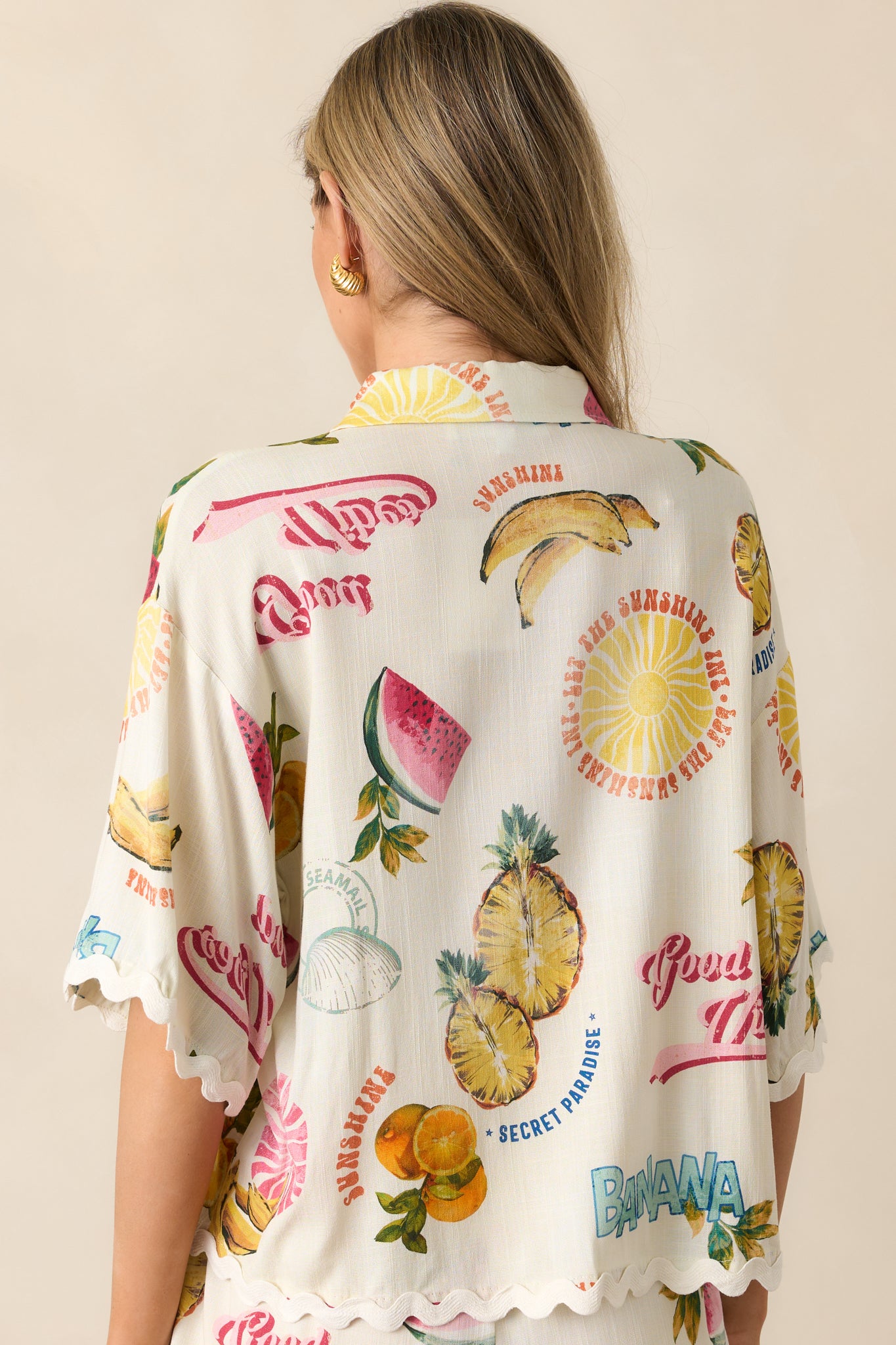 A back view of the ivory top, displaying the continuation of the tropical fruit print and oversized sleeve design.