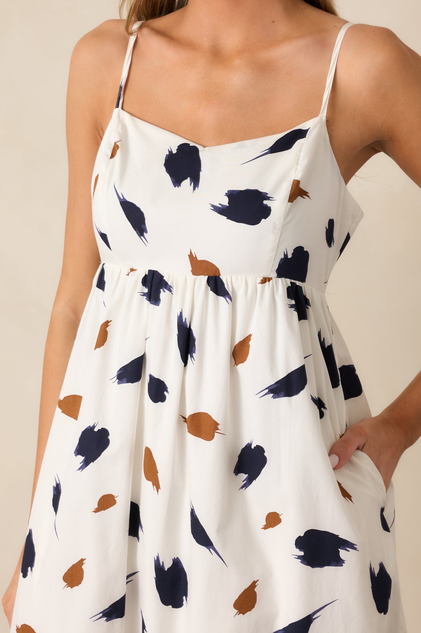 Close-up view of the ivory dress showing the intricate brown and navy brush stroke pattern and smooth fabric texture.