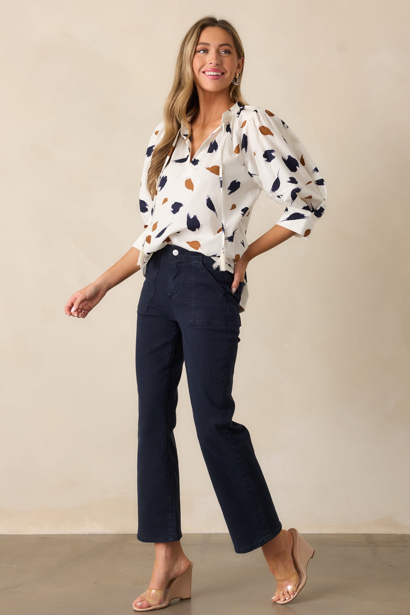 A full-length view of the navy jeans featuring a high-waisted design with large front pockets and a button and zipper closure. The jeans have a flattering, slim fit that extends down to the ankles.